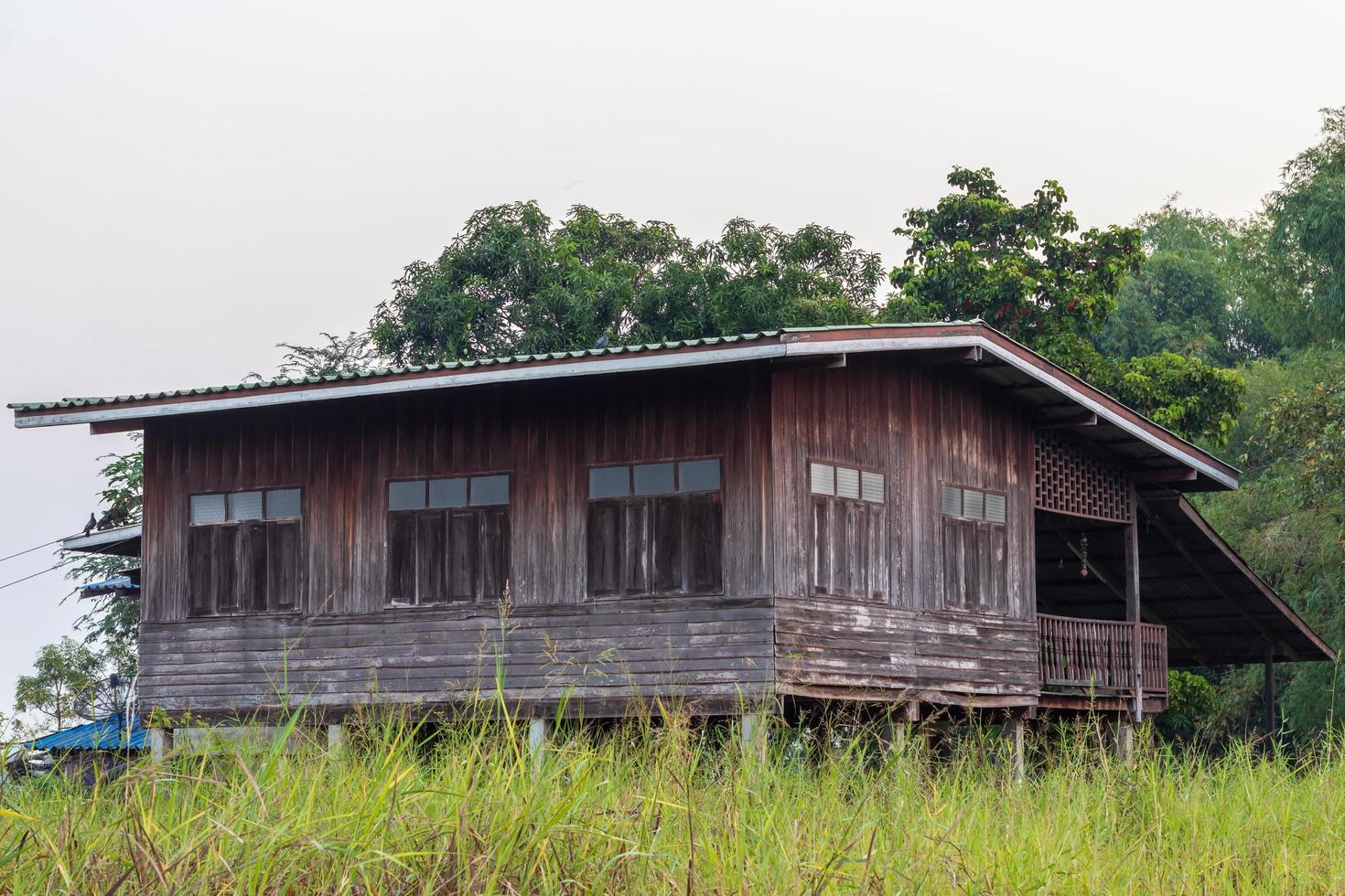 antigua casa de madera en la hierba y los árboles. foto