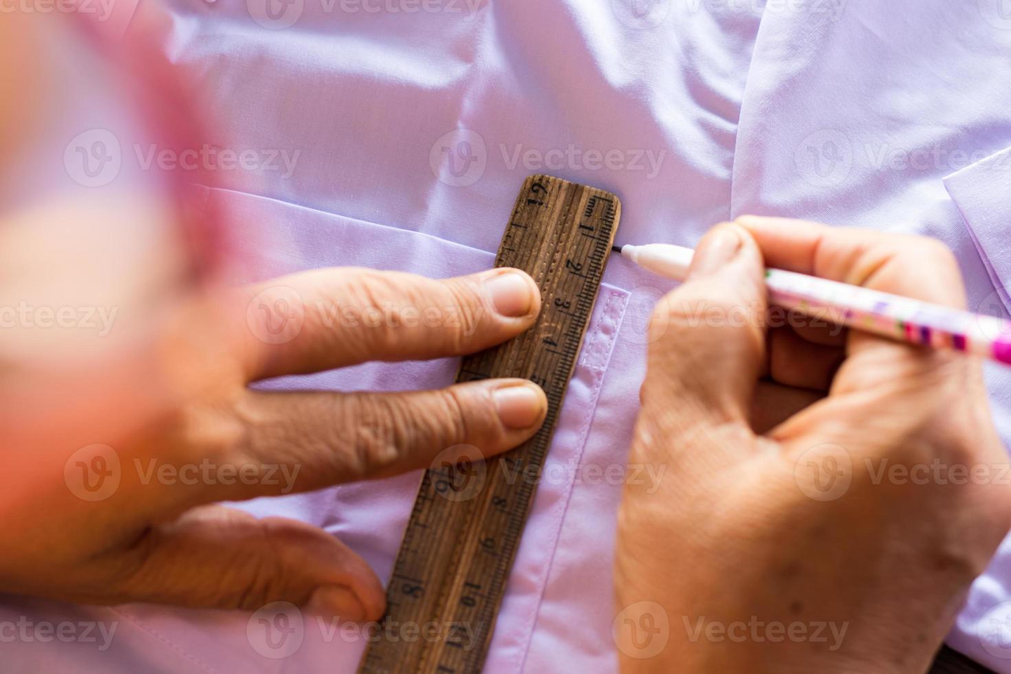 Female hand holding a pencil to draw a line with a white shirt. photo