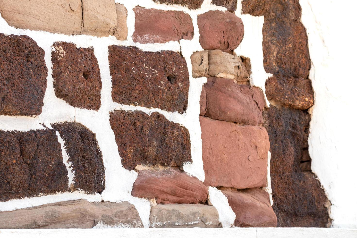 Many ancient old stones are attached to the white concrete walls. photo