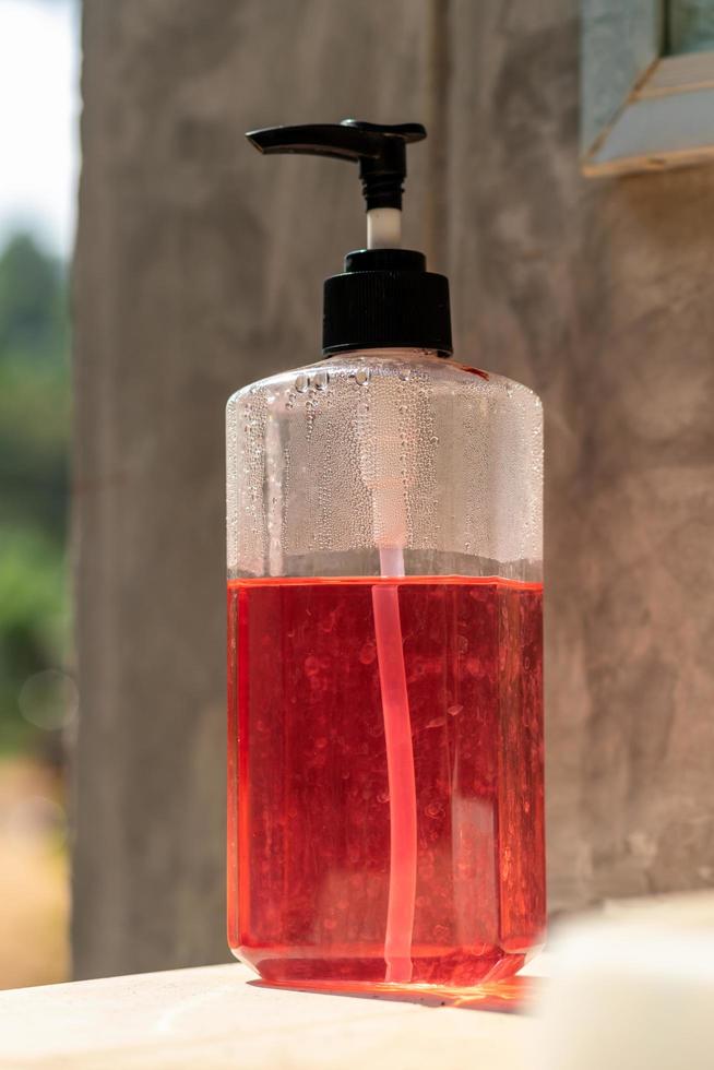 A pink and red gel bottle near the cement wall. photo