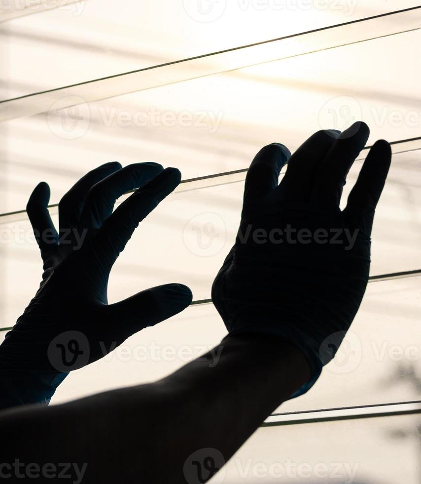 Silhouette Hand Wearing Blue Gloves With Light Louvers. photo