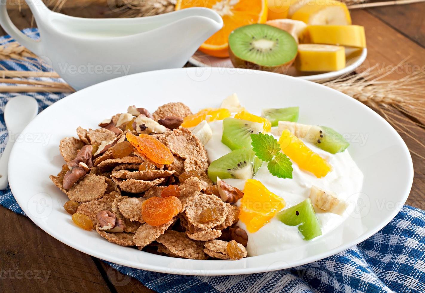 Healthy dessert with muesli and fruit in a white plate on the table photo