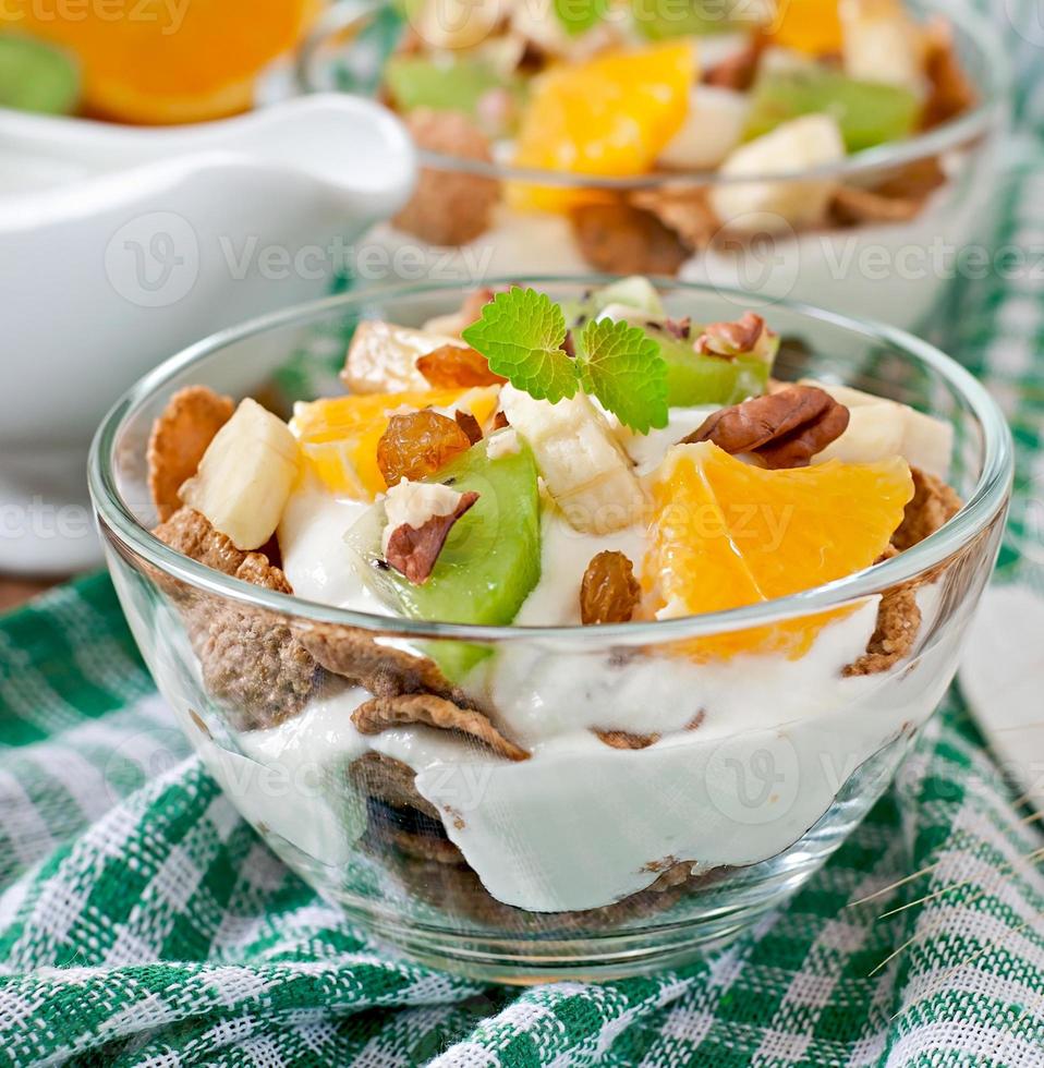 Healthy dessert with muesli and fruit in a glass bowl on the table photo