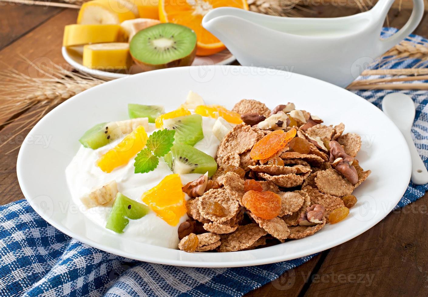 Healthy dessert with muesli and fruit in a white plate on the table photo