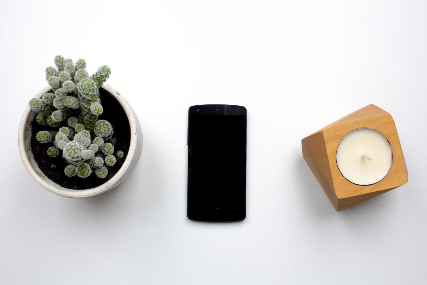 black cellphone on white background, top view of smartphone and interior decorations photo