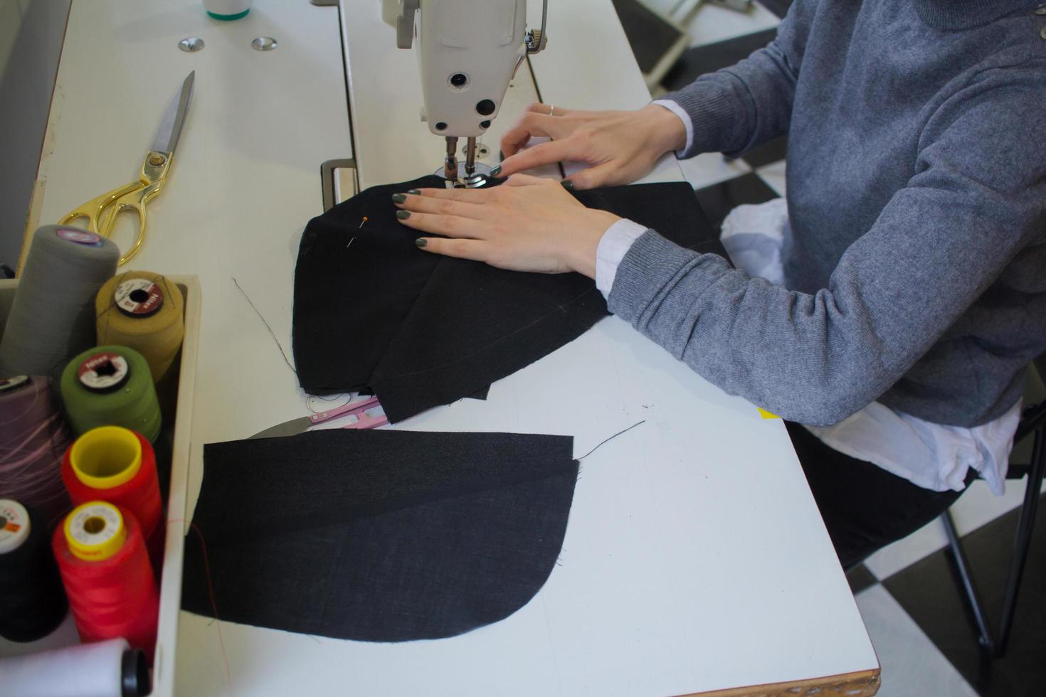 seamstress at work on the table, tailor woman work in studio with clothes photo
