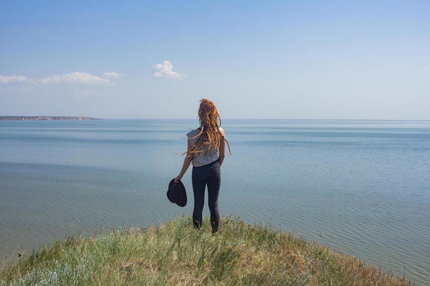 minimalistic landscape with clay cliffs and sea and young woman hiker photo