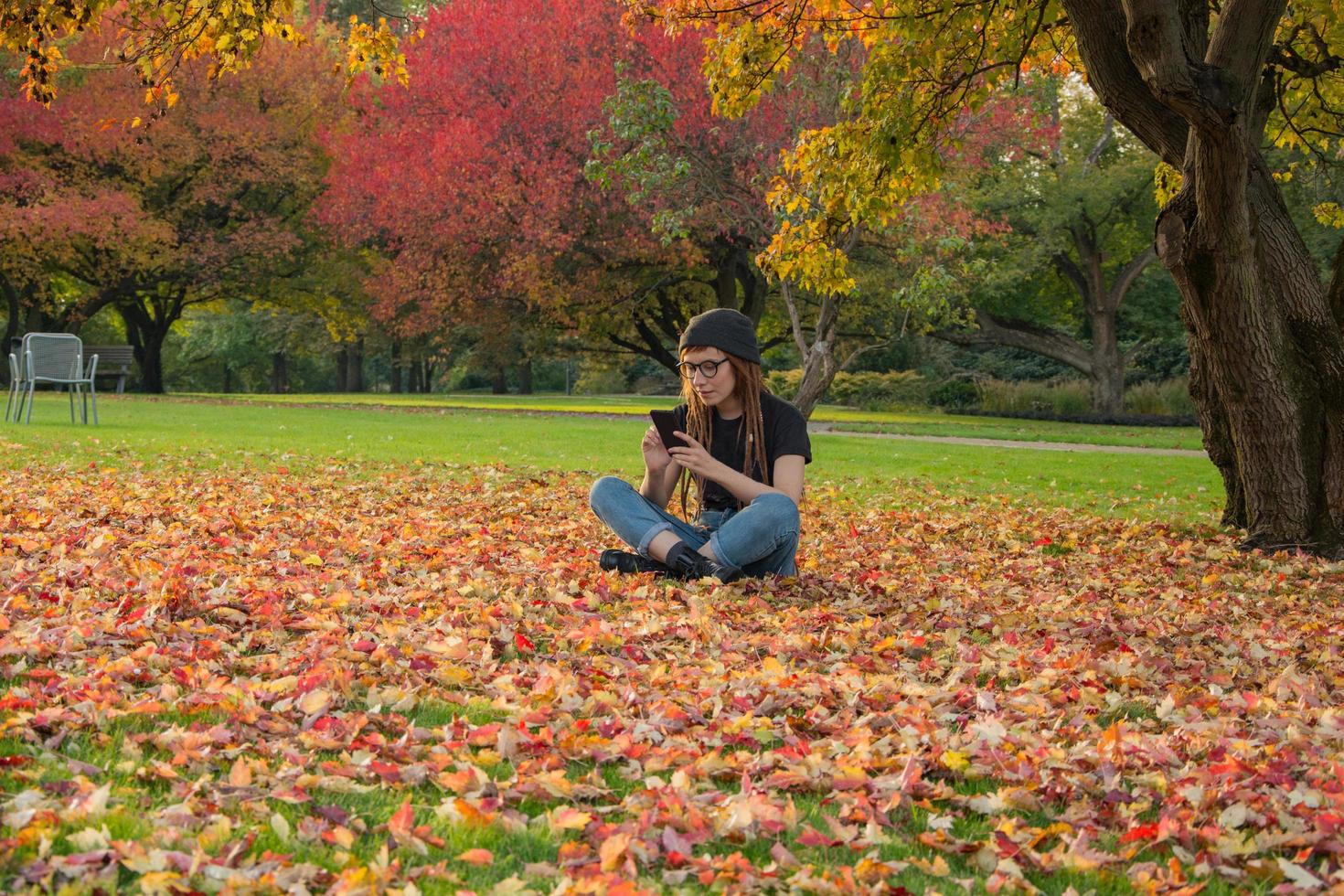 young womnan with red dreadlocks amd glasses relaxing in the autumn park photo