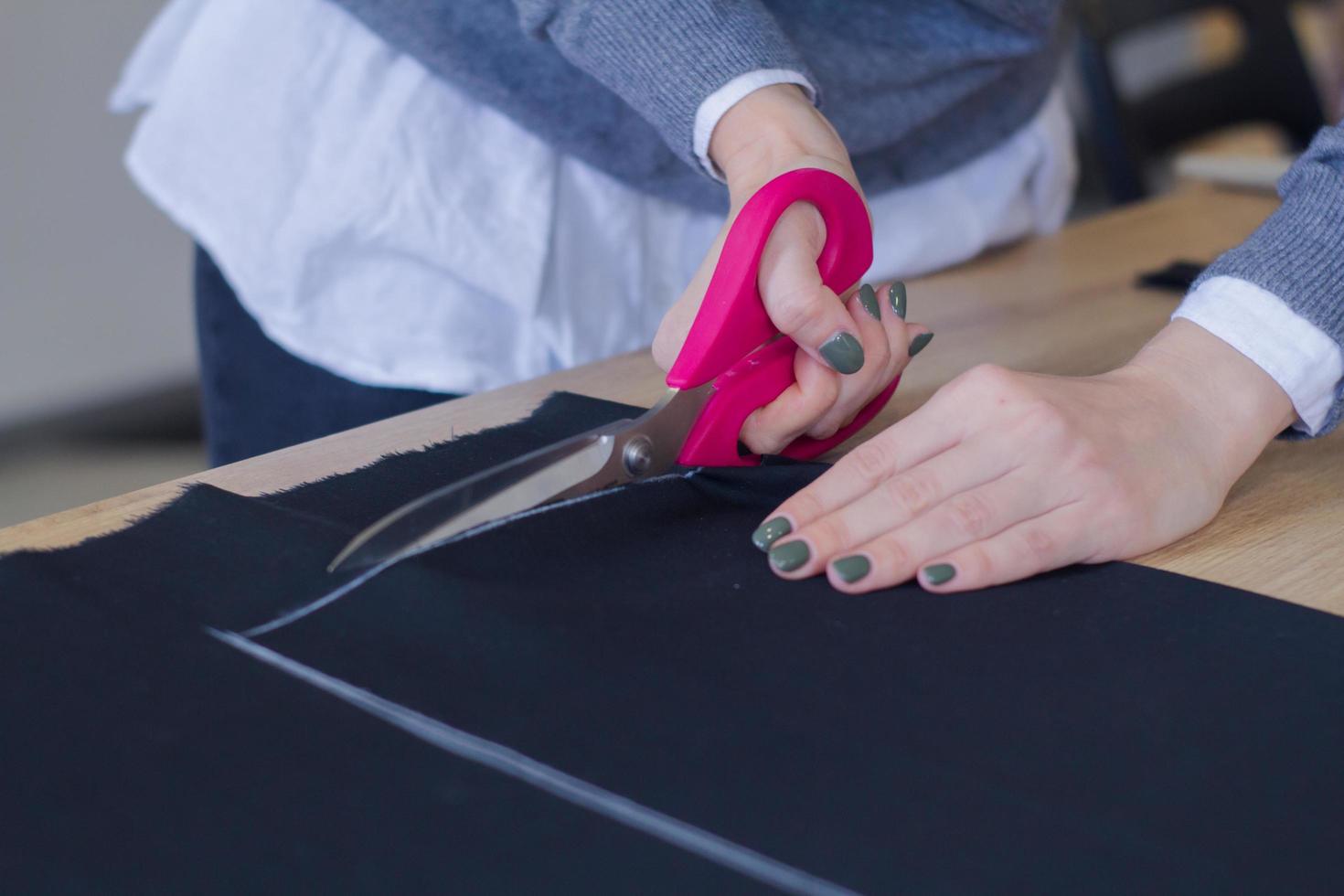 seamstress at work on the table, tailor woman work in studio with clothes photo