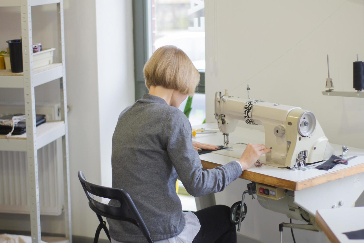 costurera en el trabajo sobre la mesa, sastre mujer trabaja en estudio con ropa foto