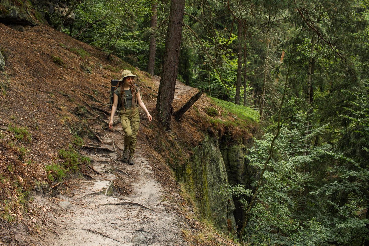 mujer joven caminando por el prado de primavera, las montañas y el bosque en el fondo foto