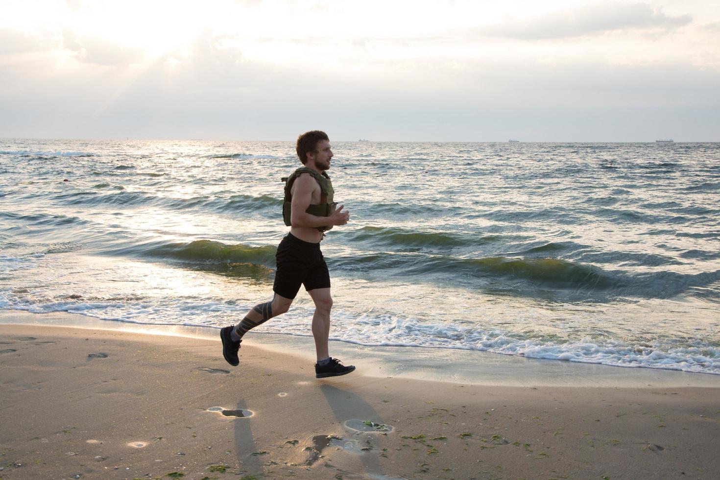 Young bearded athlete training outdoor with weighted vest, exercise with military plate carrier photo