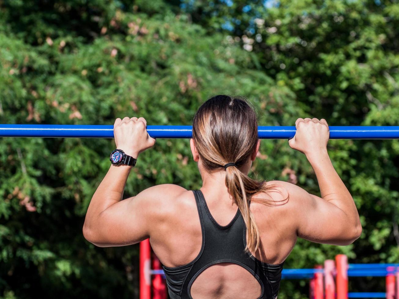 Young strong woman training outdoors in summer time, female professional athlete do exercises in the park photo