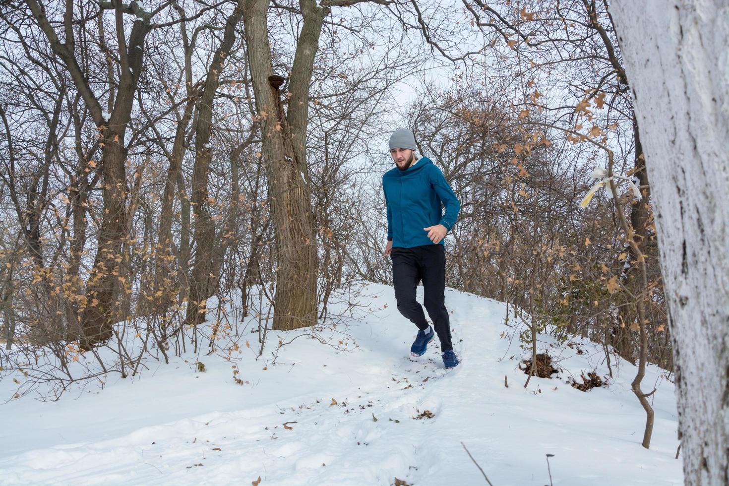 joven corredor masculino entrenando al aire libre en invierno, el hombre corre en la nieve foto