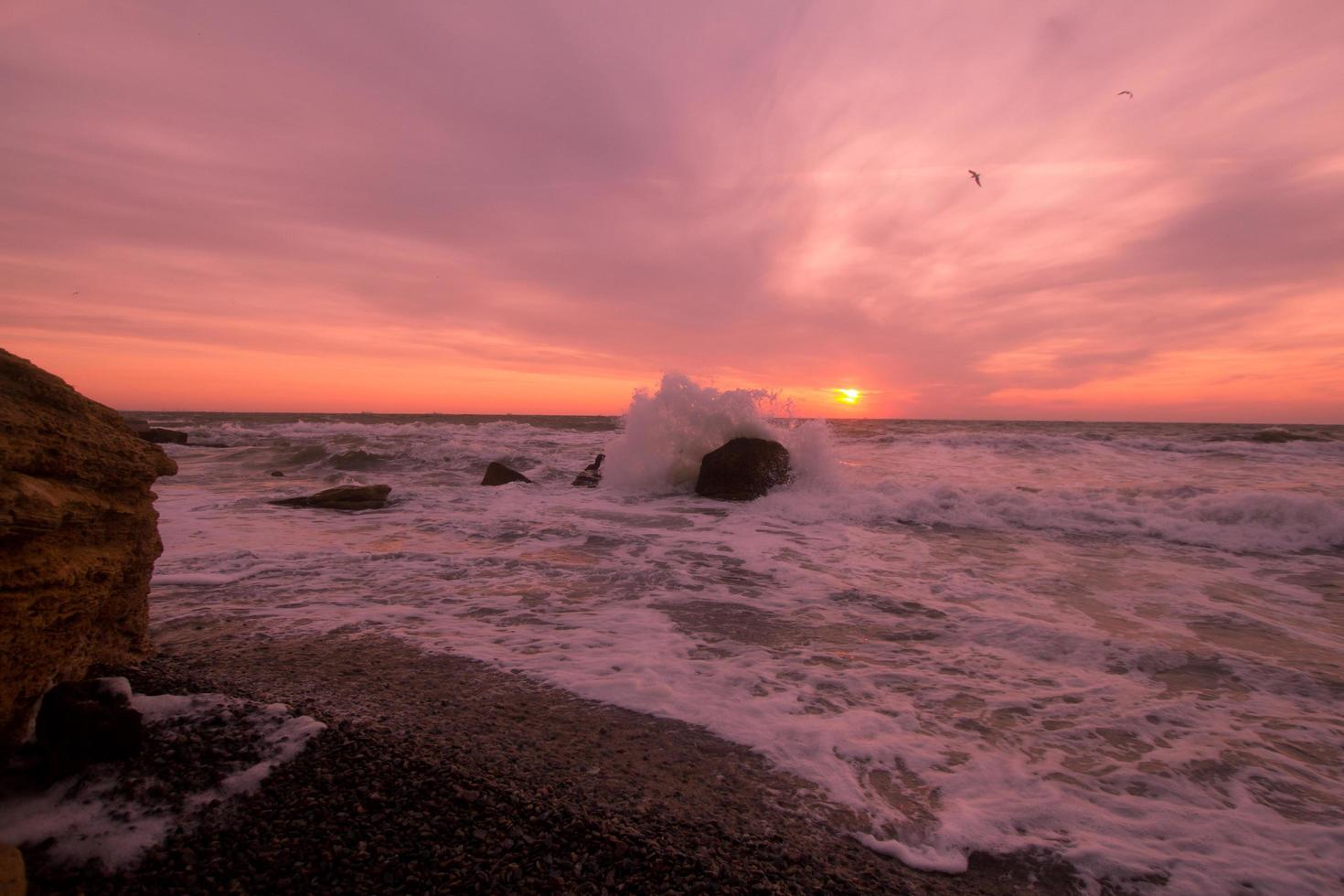 hermoso paisaje marino al amanecer, colorido cielo rosa y naranja y tormenta en el mar. foto