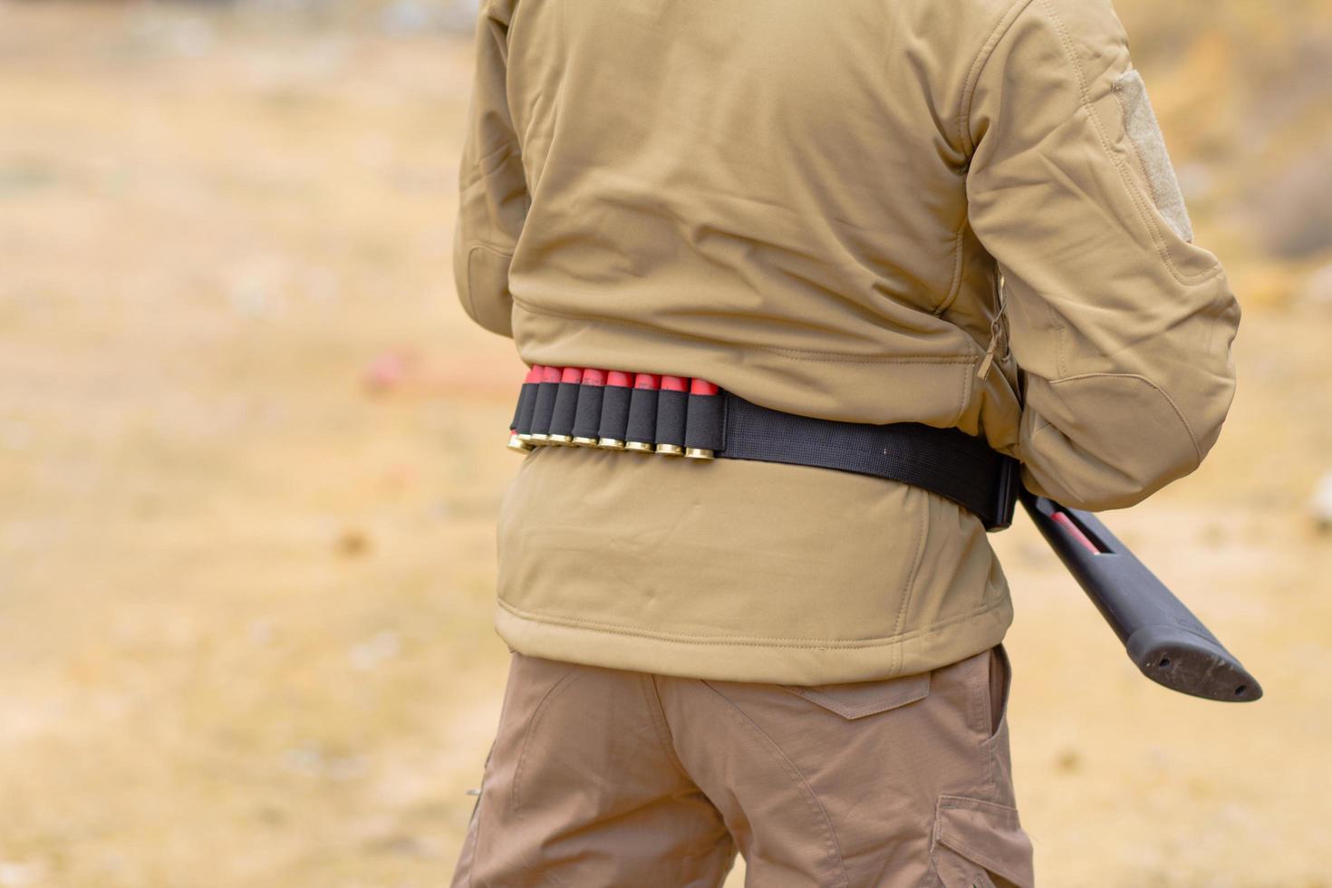 Male training with pump action shotgun outdoors in field. photo