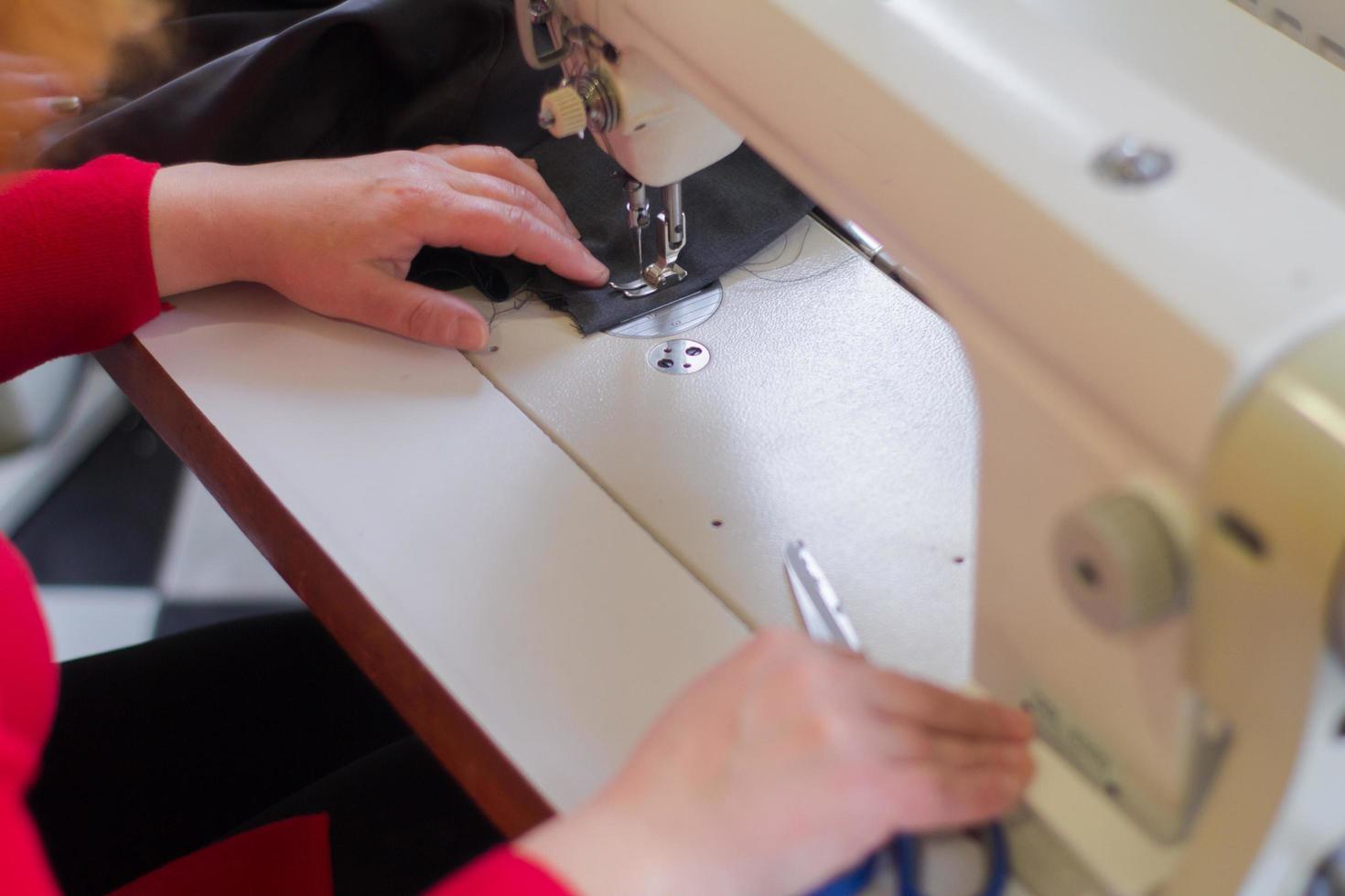 seamstress at work on the table, tailor woman work in studio with clothes photo