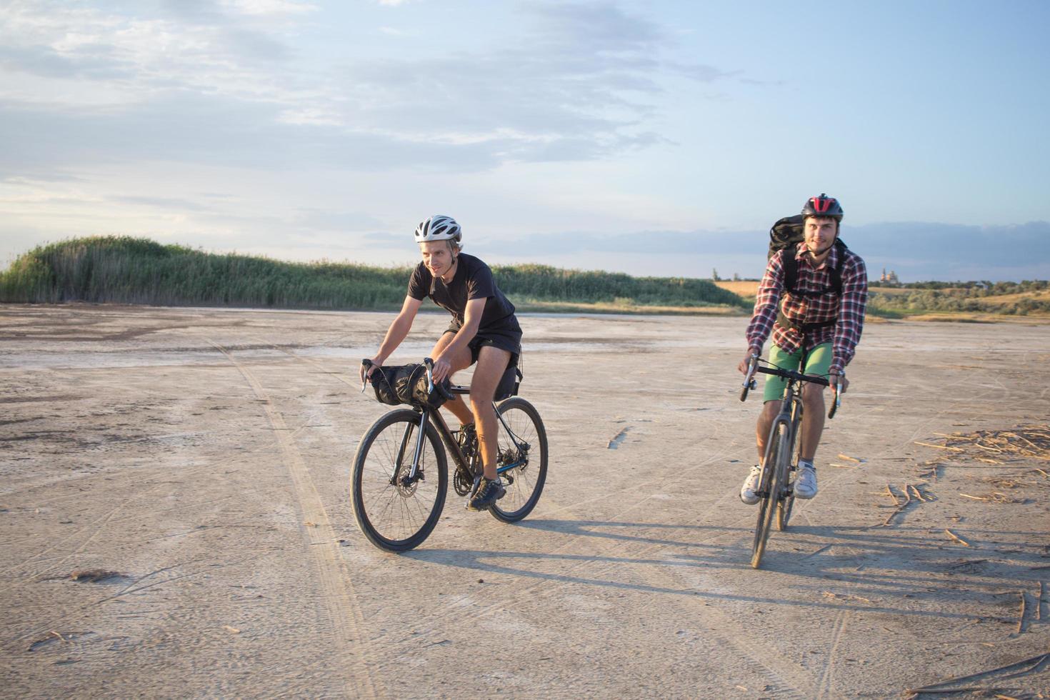 Two young male on a touring bicycle with backpacks and helmets in the desert on a bicycle trip photo