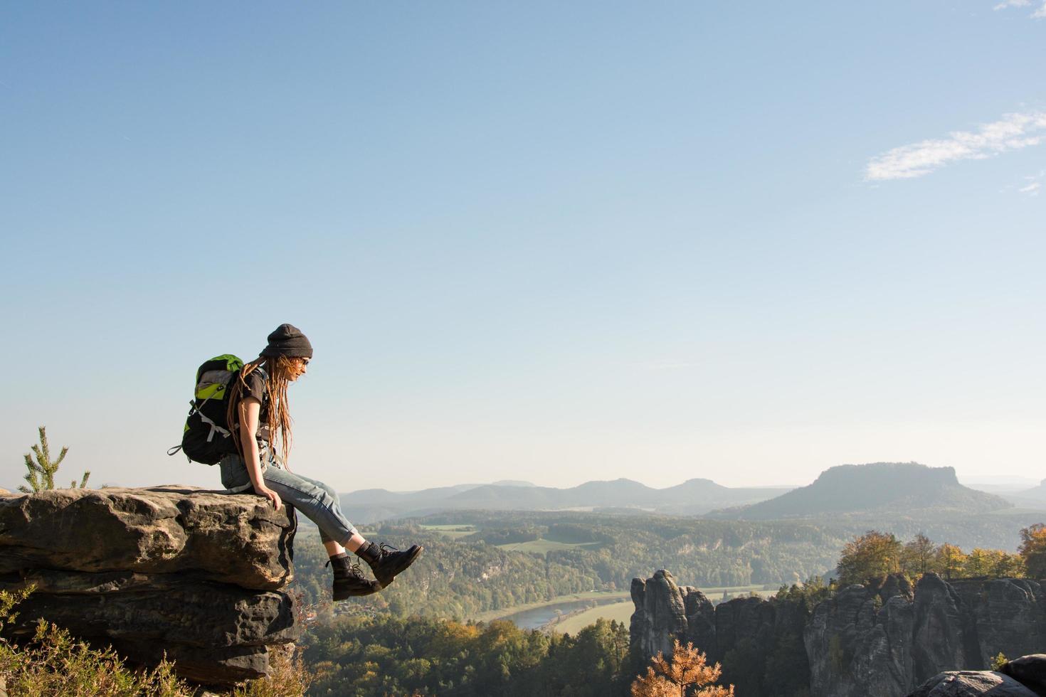 Youmg woman with backpack stand on the old german castle in saxon switzerland national park photo