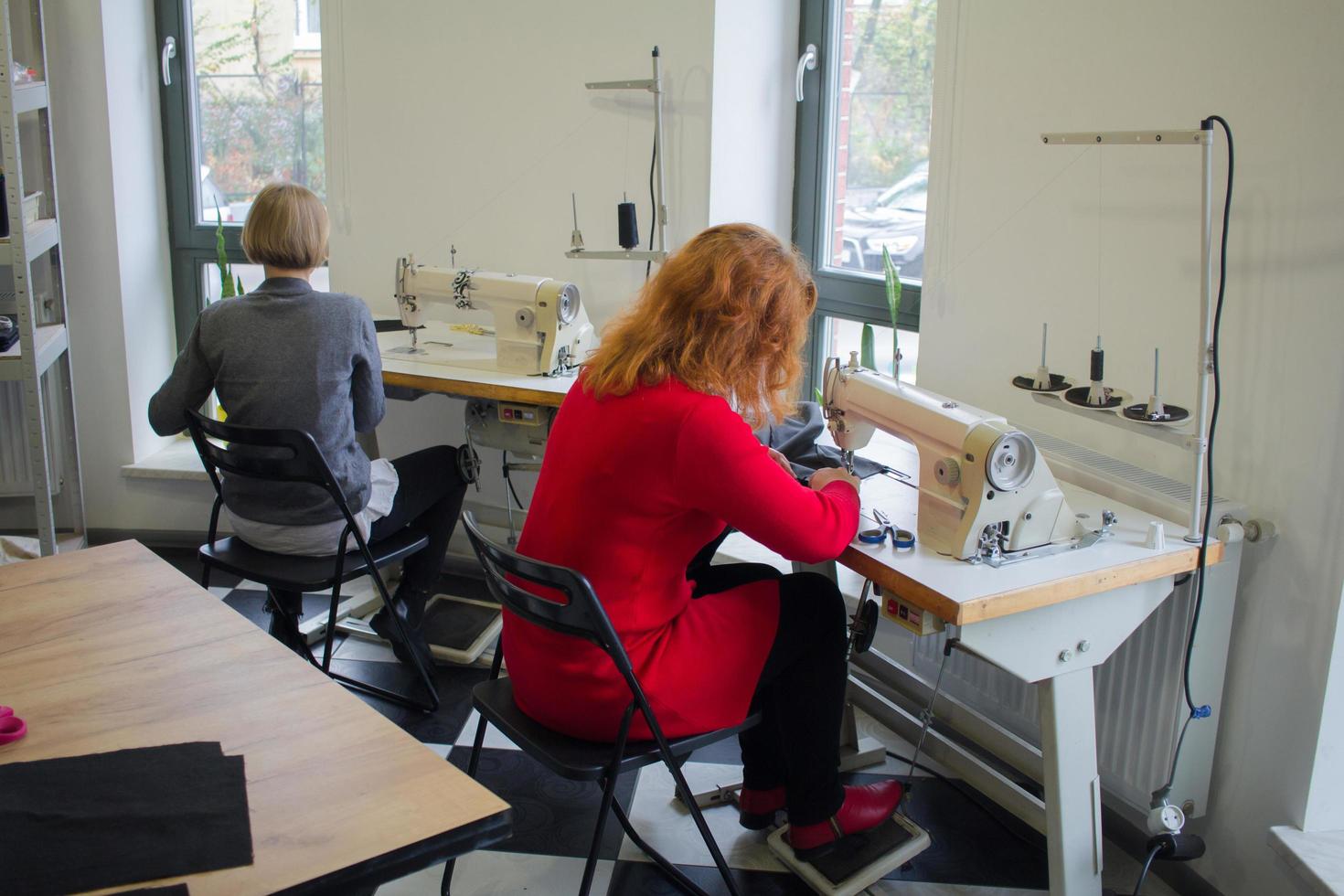 seamstress at work on the table, tailor woman work in studio with clothes photo