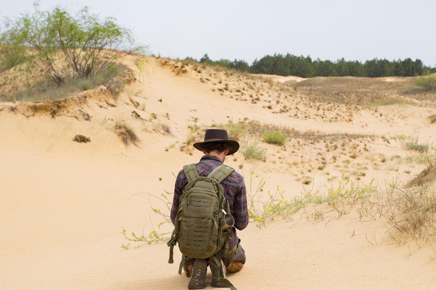 vista trasera de un joven excursionista con sombrero de vaquero caminando al aire libre en verano. viajero inconformista. foto