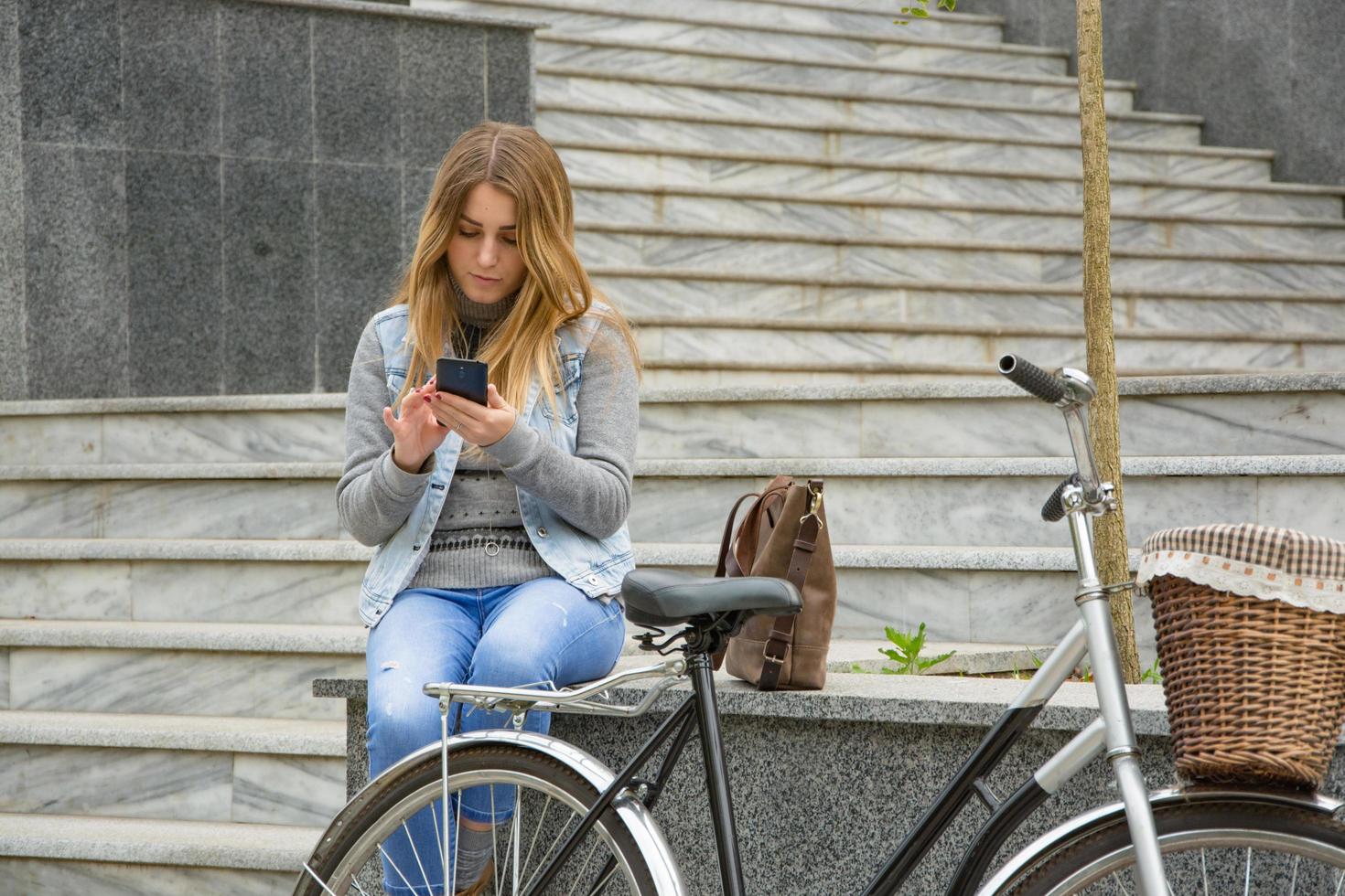 young woman bicycle rider use cellphone, urban background photo