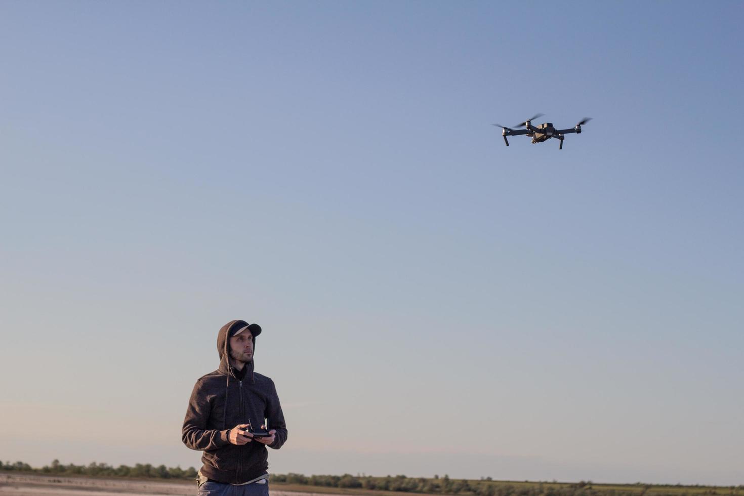 picture of black flaying quadrocopter dron and pilot siluette in sunset light background, tourist use dron helicopter to photography or filming desert landscapes photo