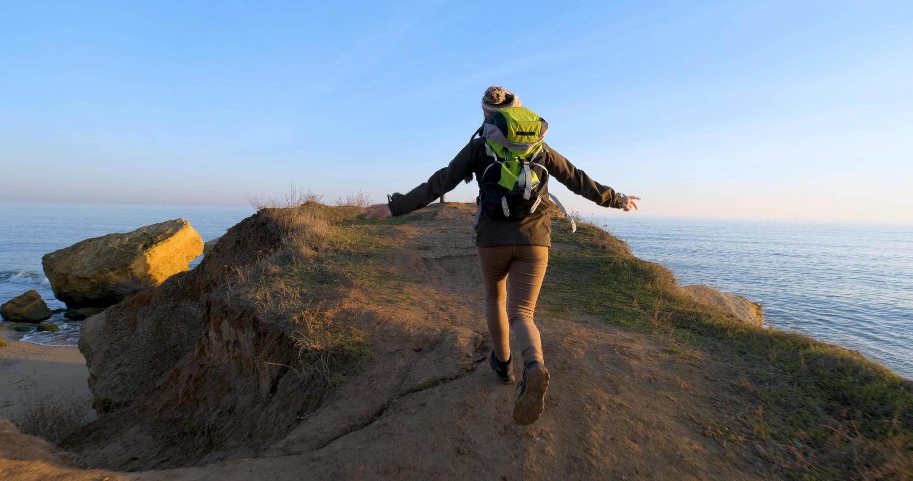 Young female travelr with backpack and retro film camera travel in the autumn mountains near sea photo