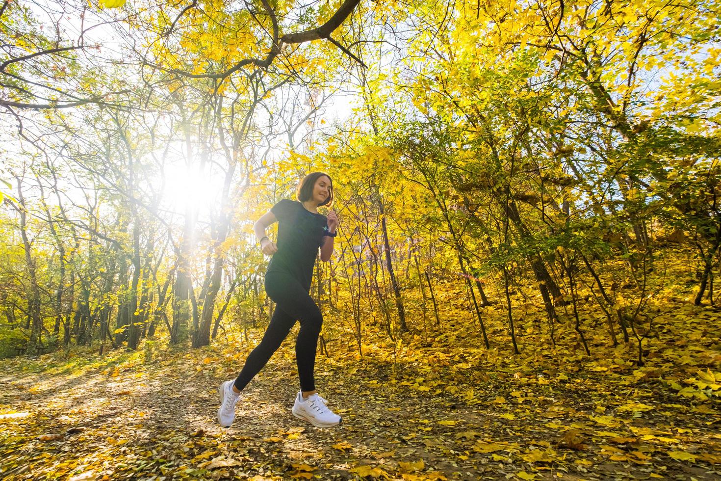 joven corredora feliz entrenando en el soleado parque de otoño foto