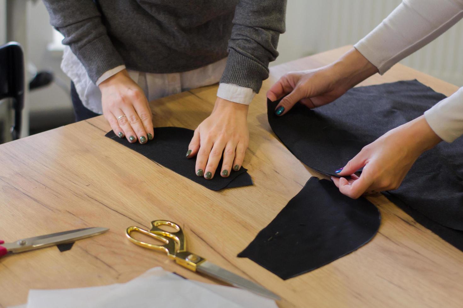 costurera en el trabajo sobre la mesa, sastre mujer trabaja en estudio con ropa foto