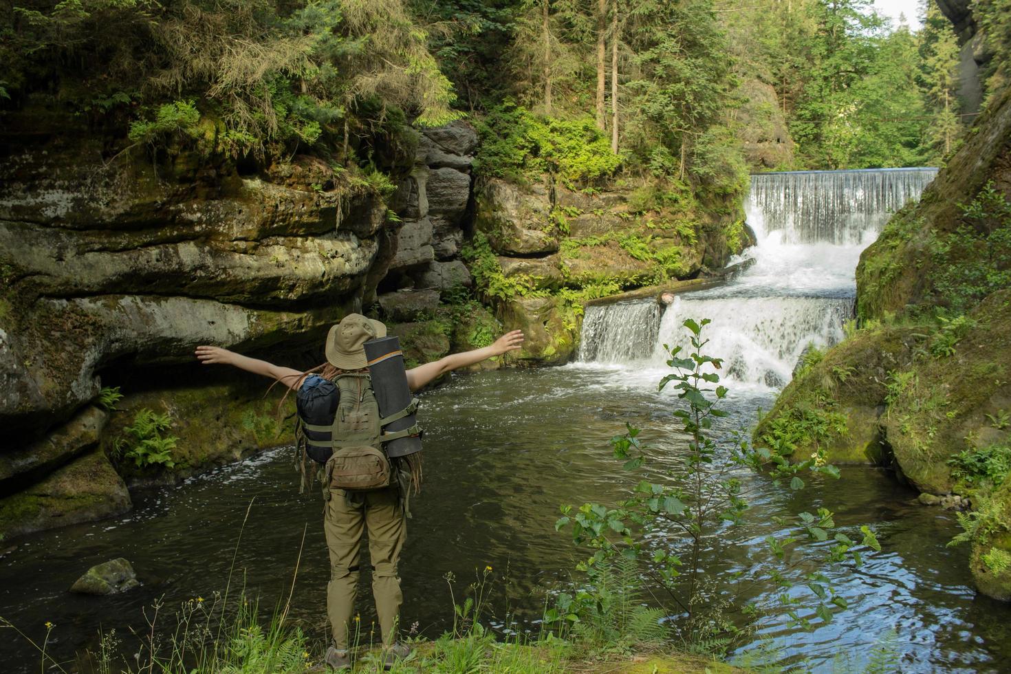 Young woman hiker posing near the river in bohemian switzerland national park, female traveler in mountains of czech republic photo