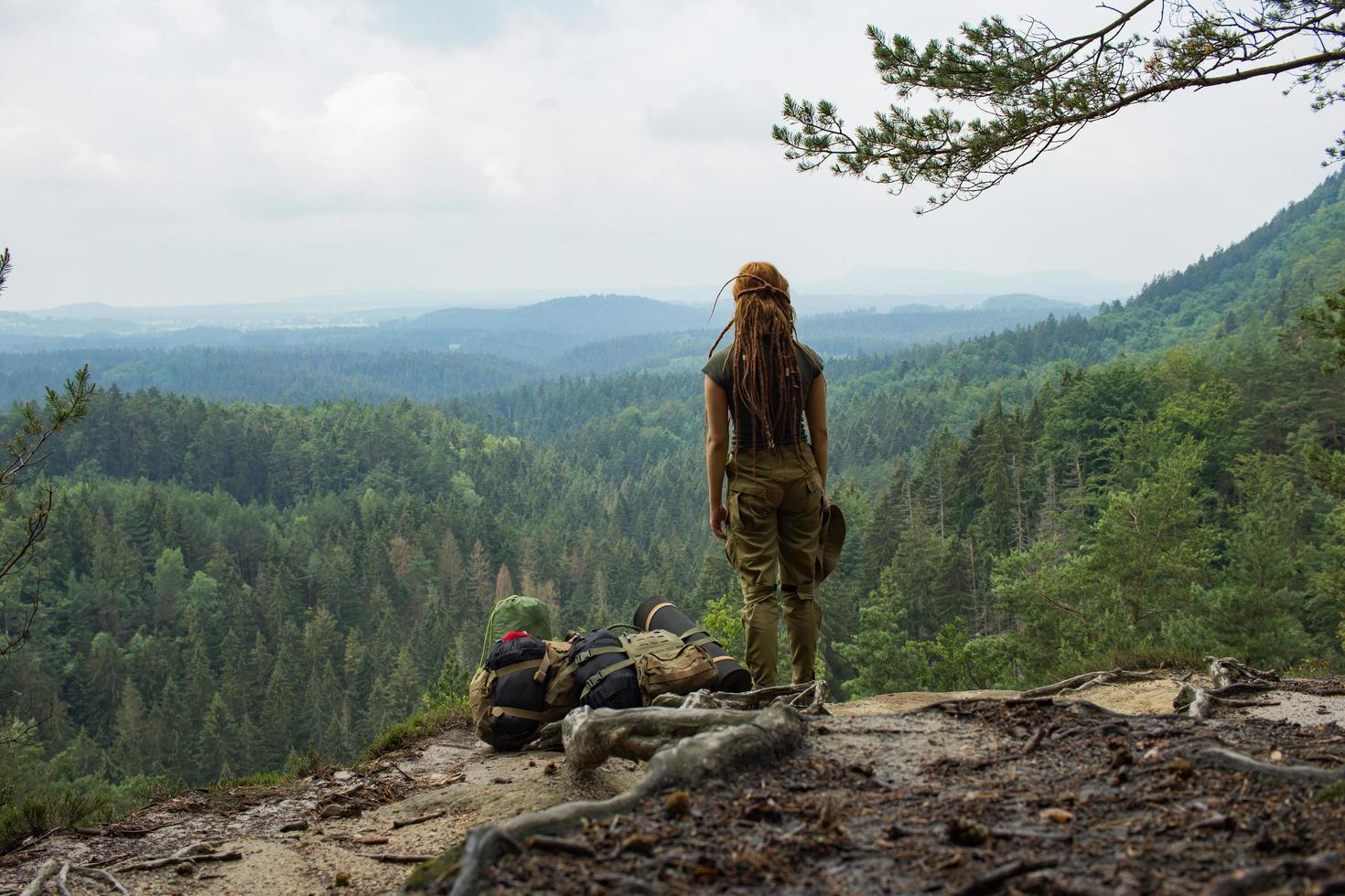 Young woman hiking on the spring meadow, mountains and forest on background photo