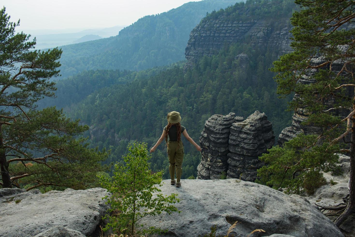 Young woman hiking on the spring meadow, mountains and forest on background photo