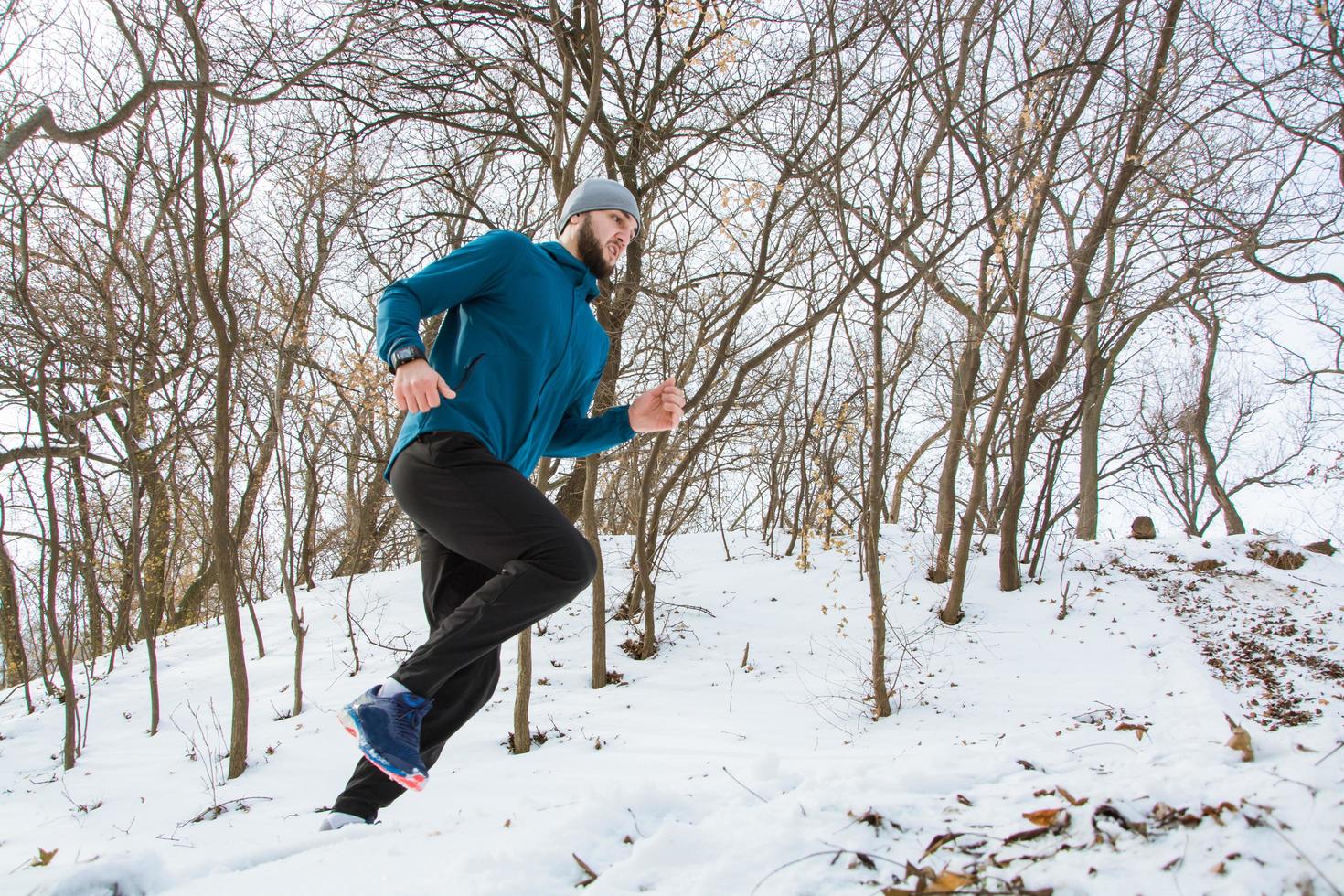 Young male runner training outdoors in winter times, man run on the snow photo