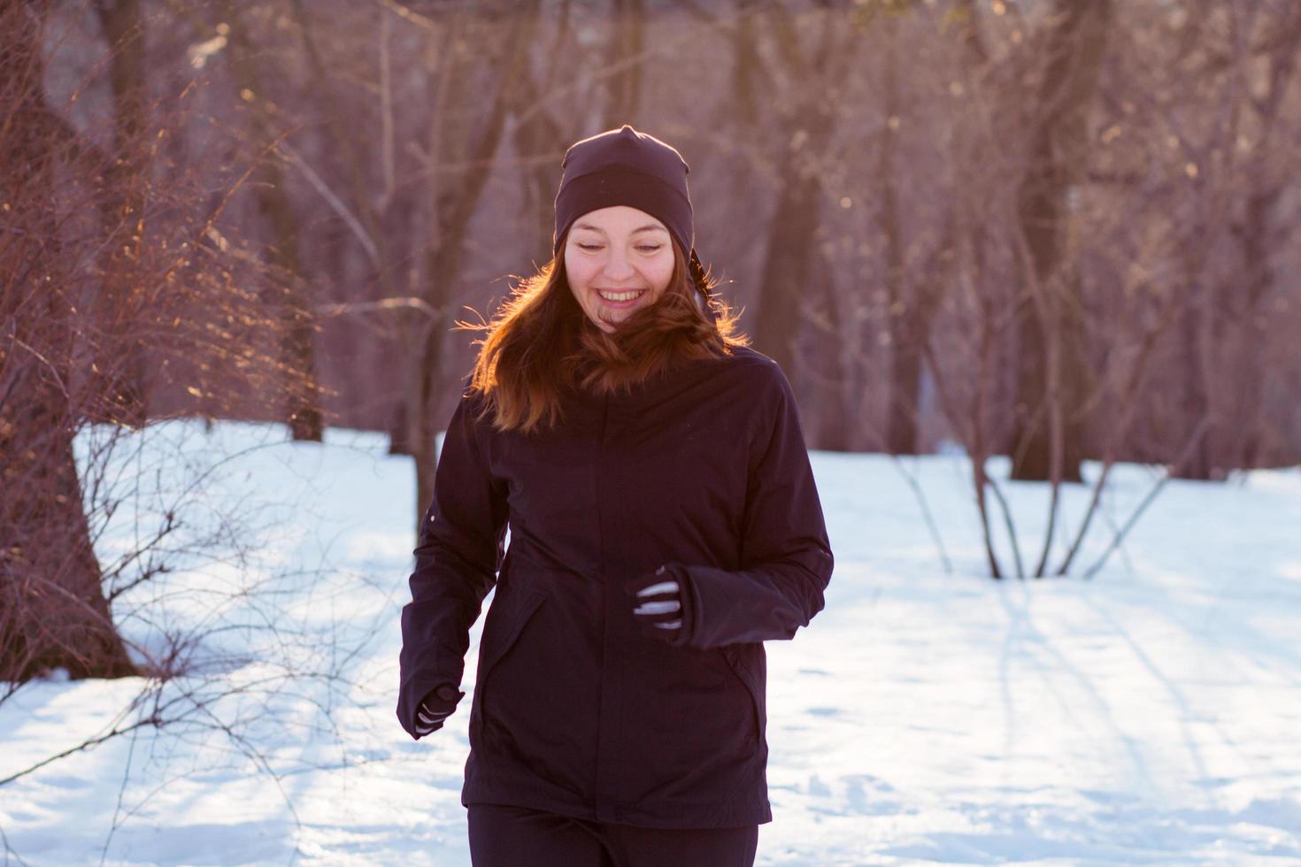 young woman athlete in black sport suit run in winter park photo