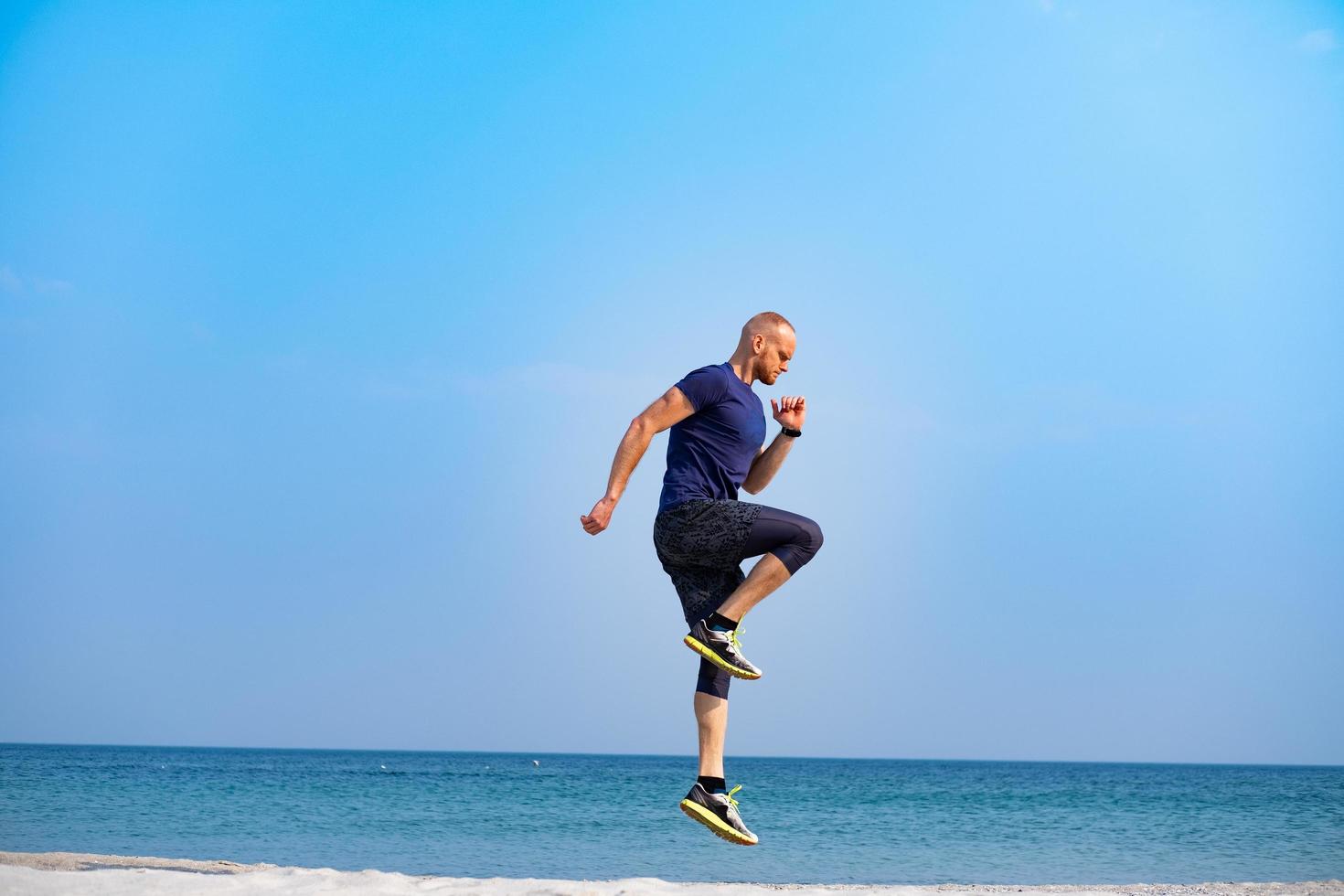Young male athlete training in sunny day on the beach photo