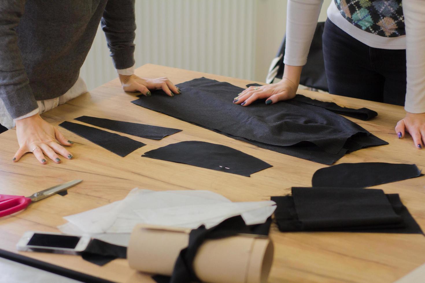 costurera en el trabajo sobre la mesa, sastre mujer trabaja en estudio con ropa foto