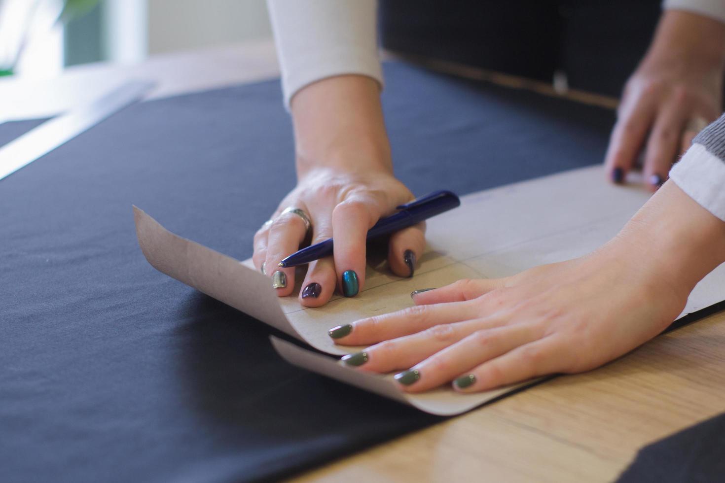 seamstress at work on the table, tailor woman work in studio with clothes photo