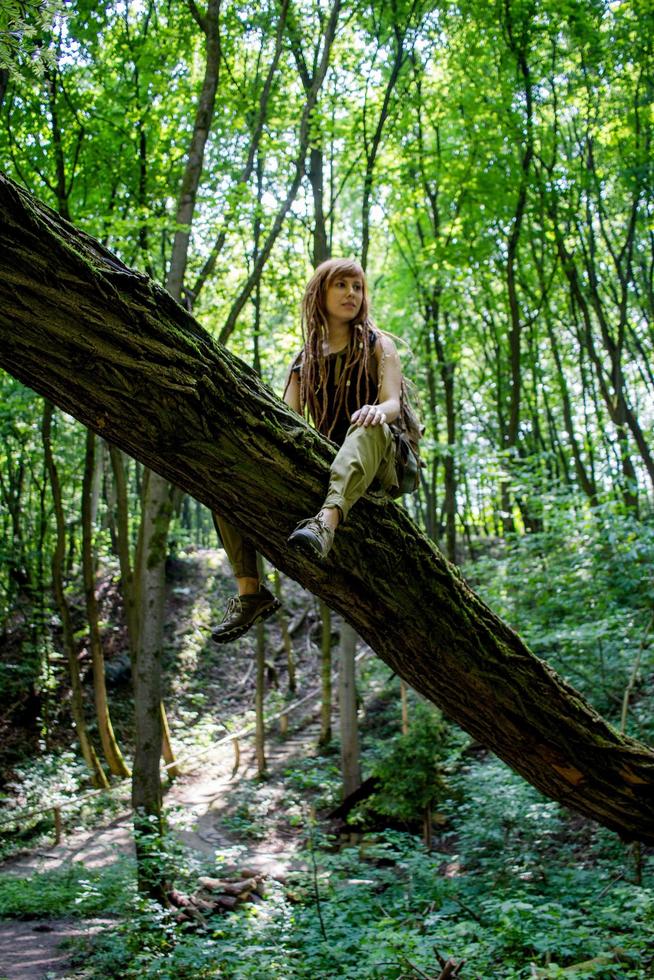 mujer joven caminando por el prado de primavera, las montañas y el bosque en el fondo foto