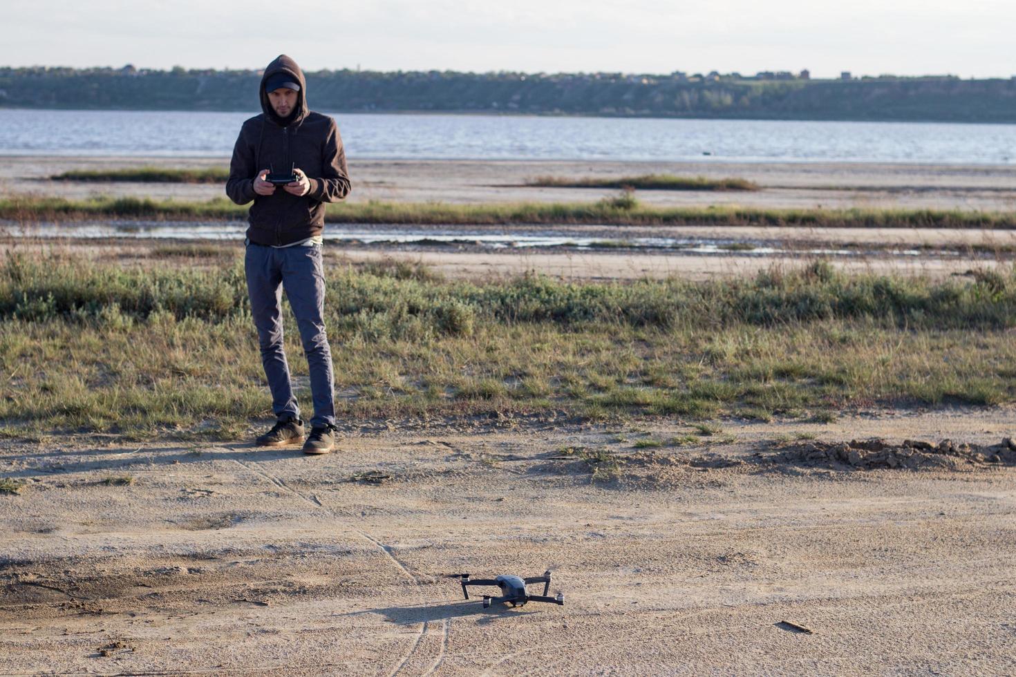 imagen de un dron de cuadricóptero desollado negro y una silueta piloto en el fondo de la luz del atardecer, un helicóptero de dron de uso turístico para fotografiar o filmar paisajes desérticos foto