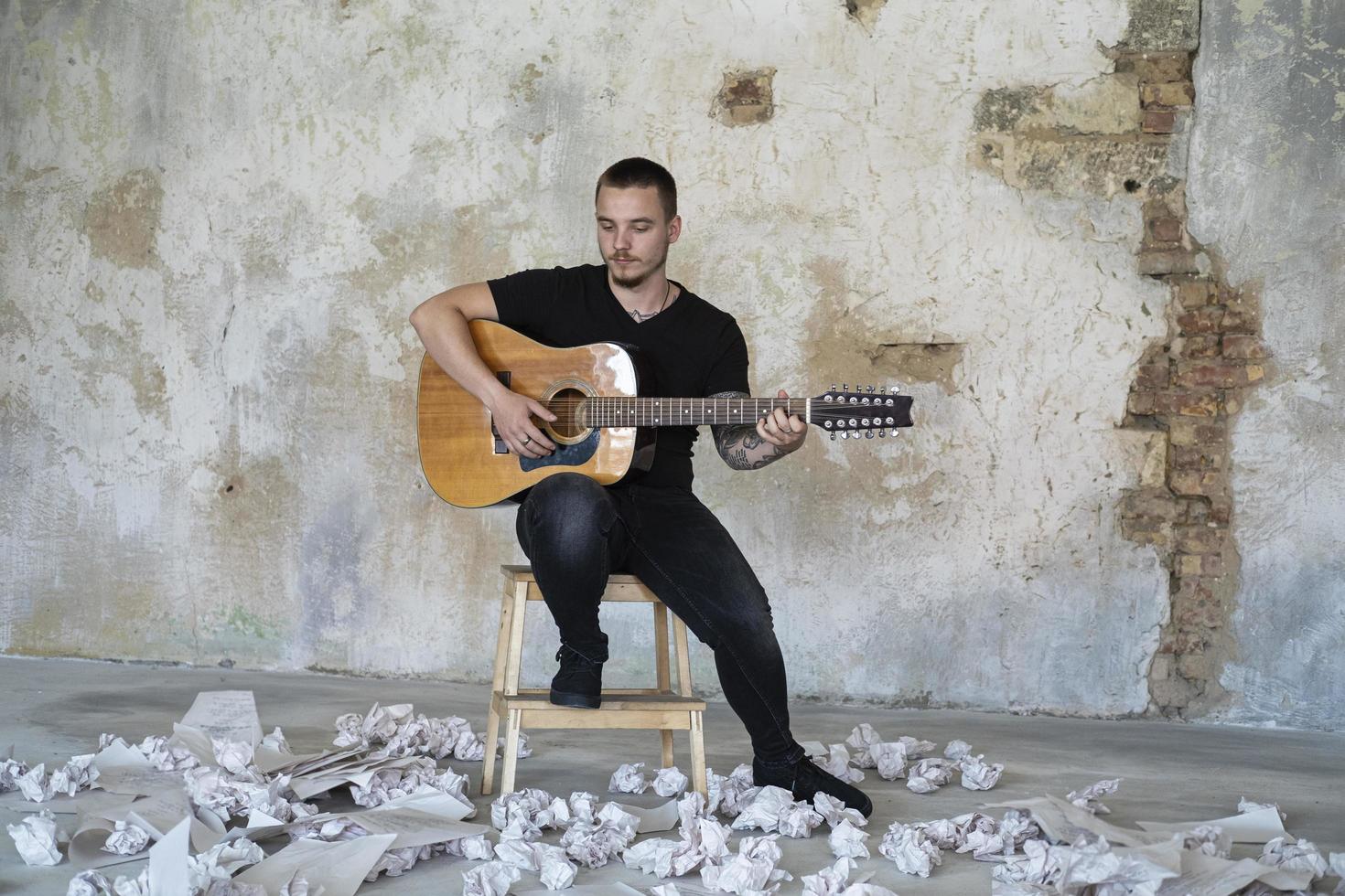 joven con guitarra en una habitación vacía, músico y compositor solo en el estudio foto