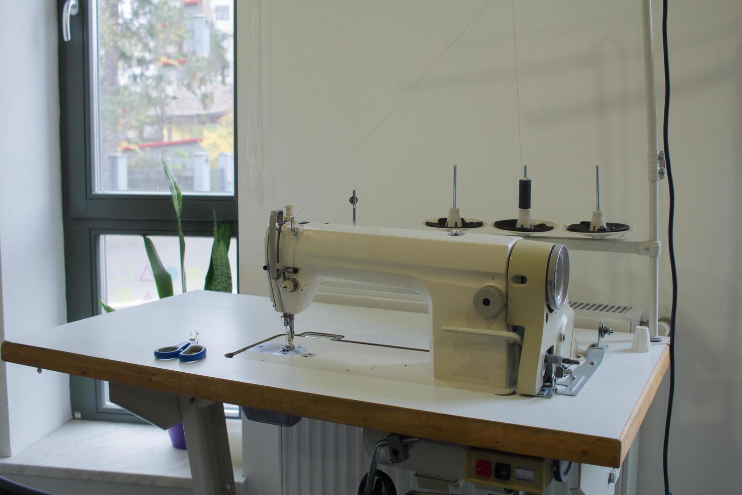 máquina de coser en la mesa de trabajo en sastrería foto