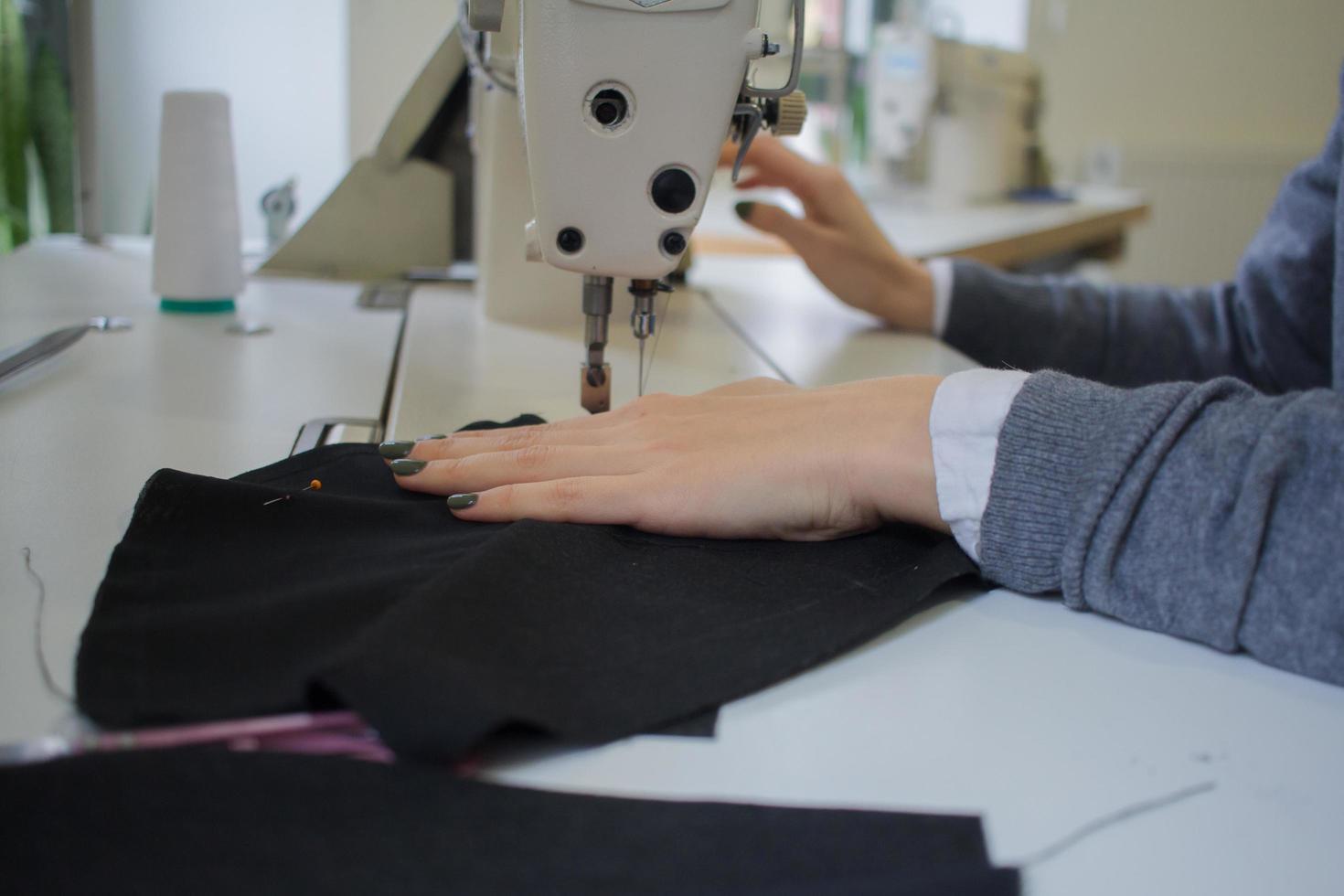 costurera en el trabajo sobre la mesa, sastre mujer trabaja en estudio con ropa foto