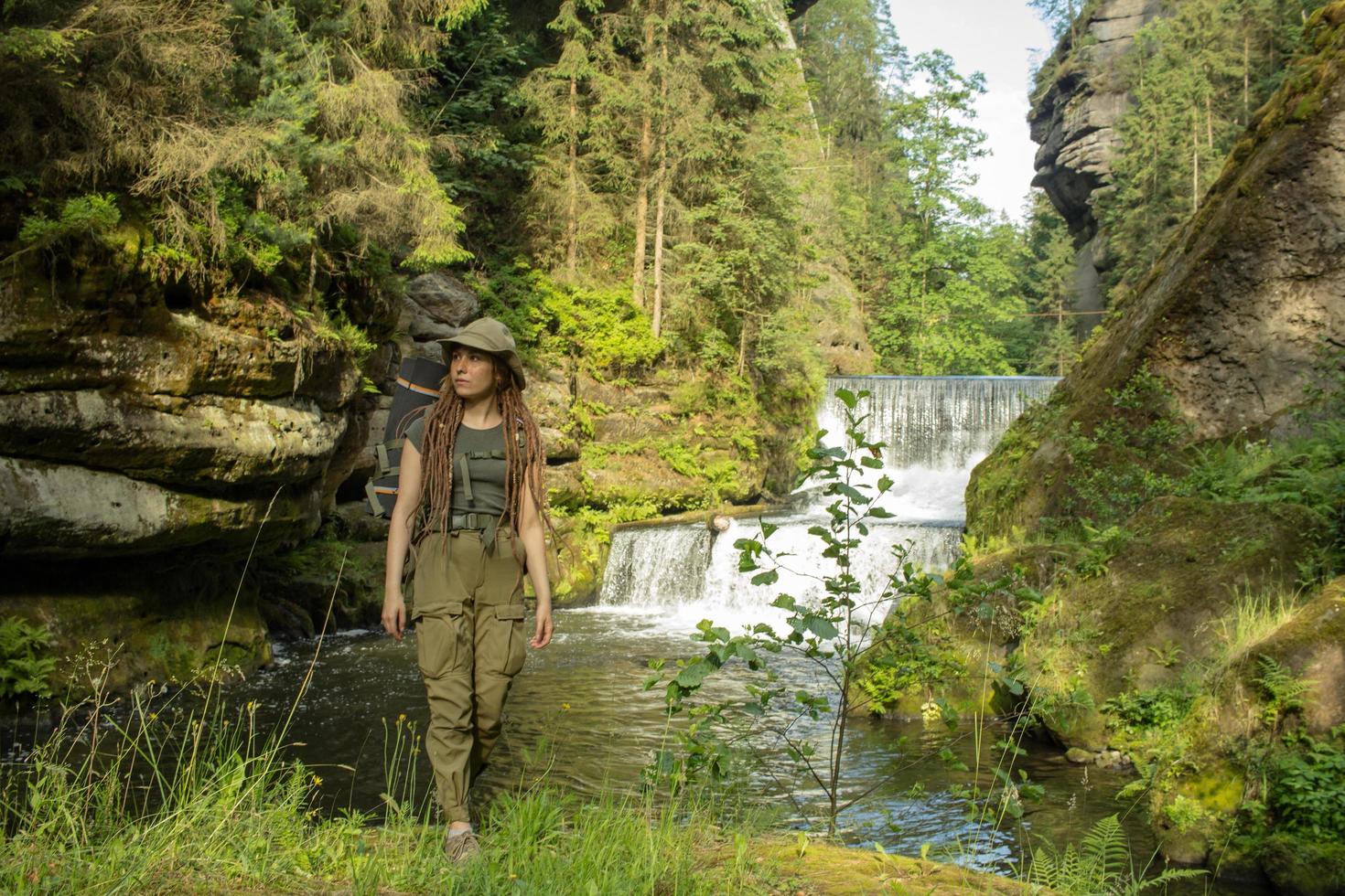 Young woman hiker posing near the river in bohemian switzerland national park, female traveler in mountains of czech republic photo