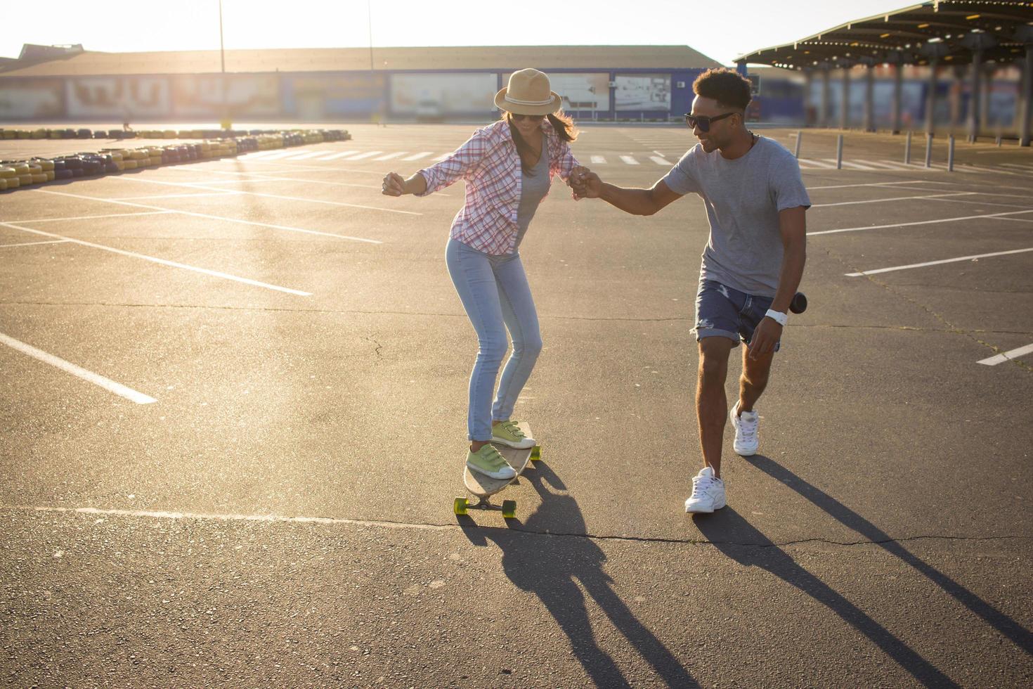 Happy young couple riding skateboard during sunrise photo