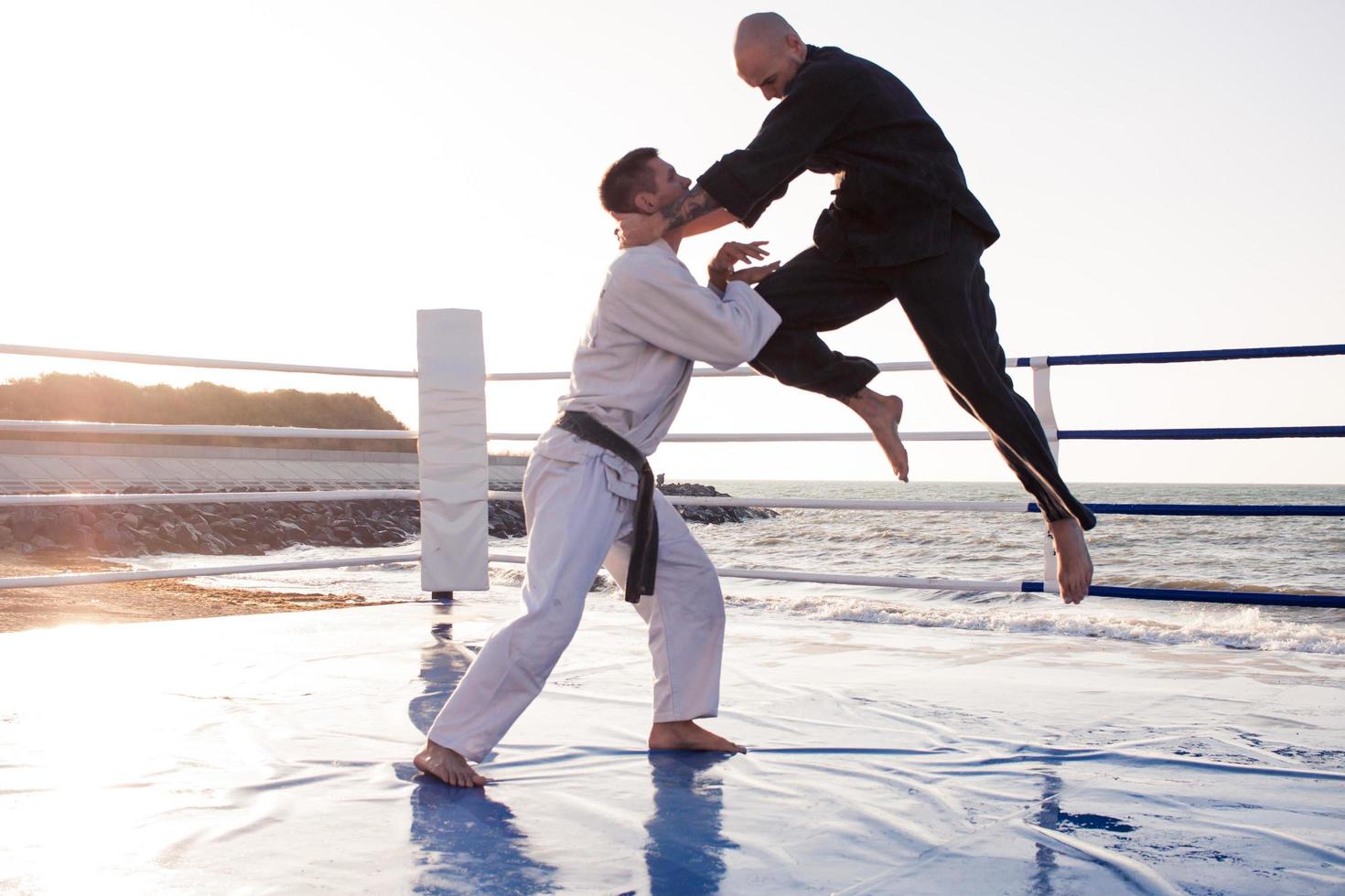 karate fighters are fighting on the beach boxing ring in morning photo