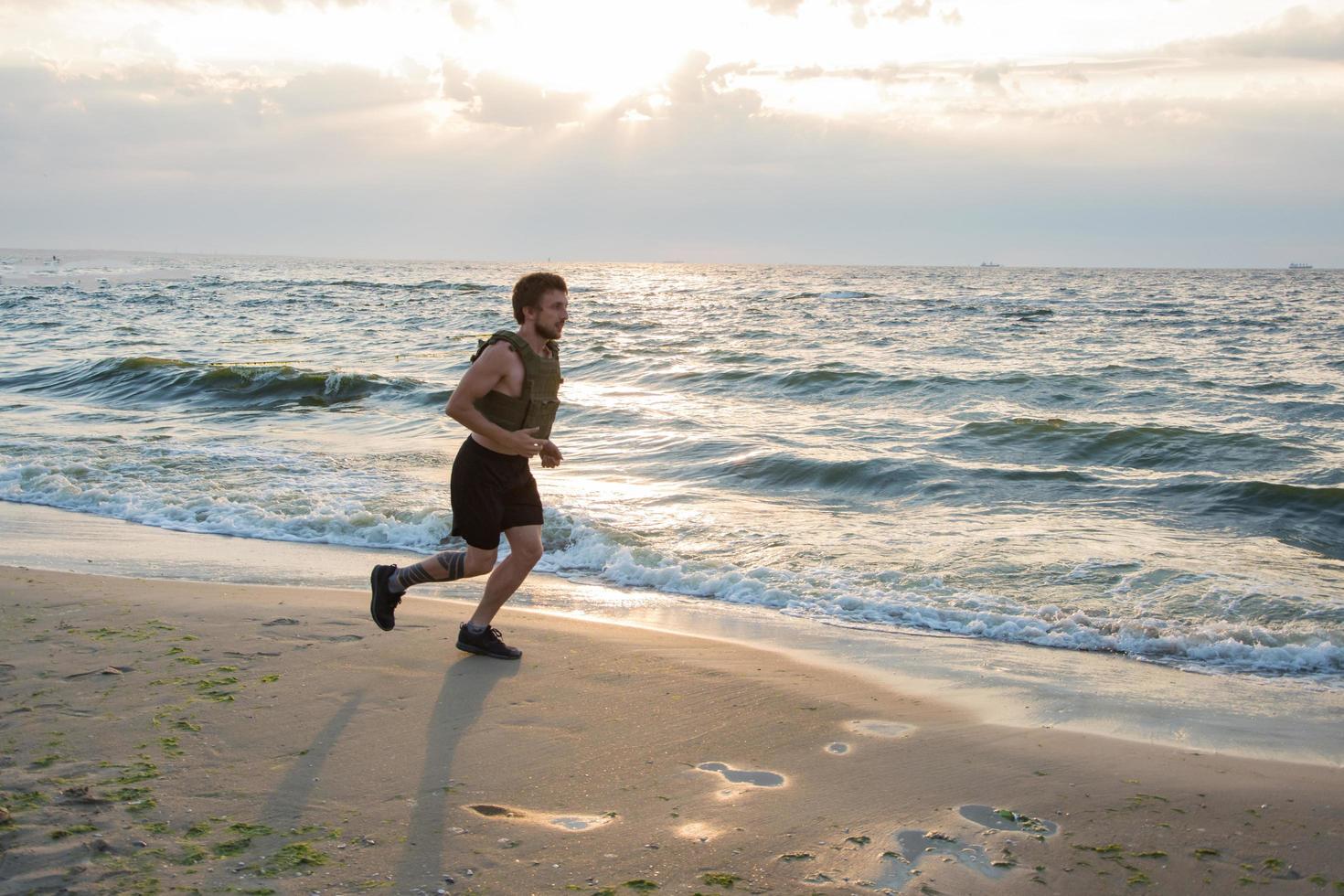 Young bearded athlete training outdoor with weighted vest, exercise with military plate carrier photo