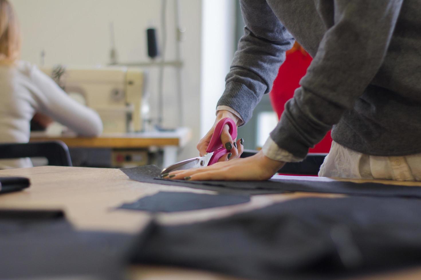 seamstress at work on the table, tailor woman work in studio with clothes photo