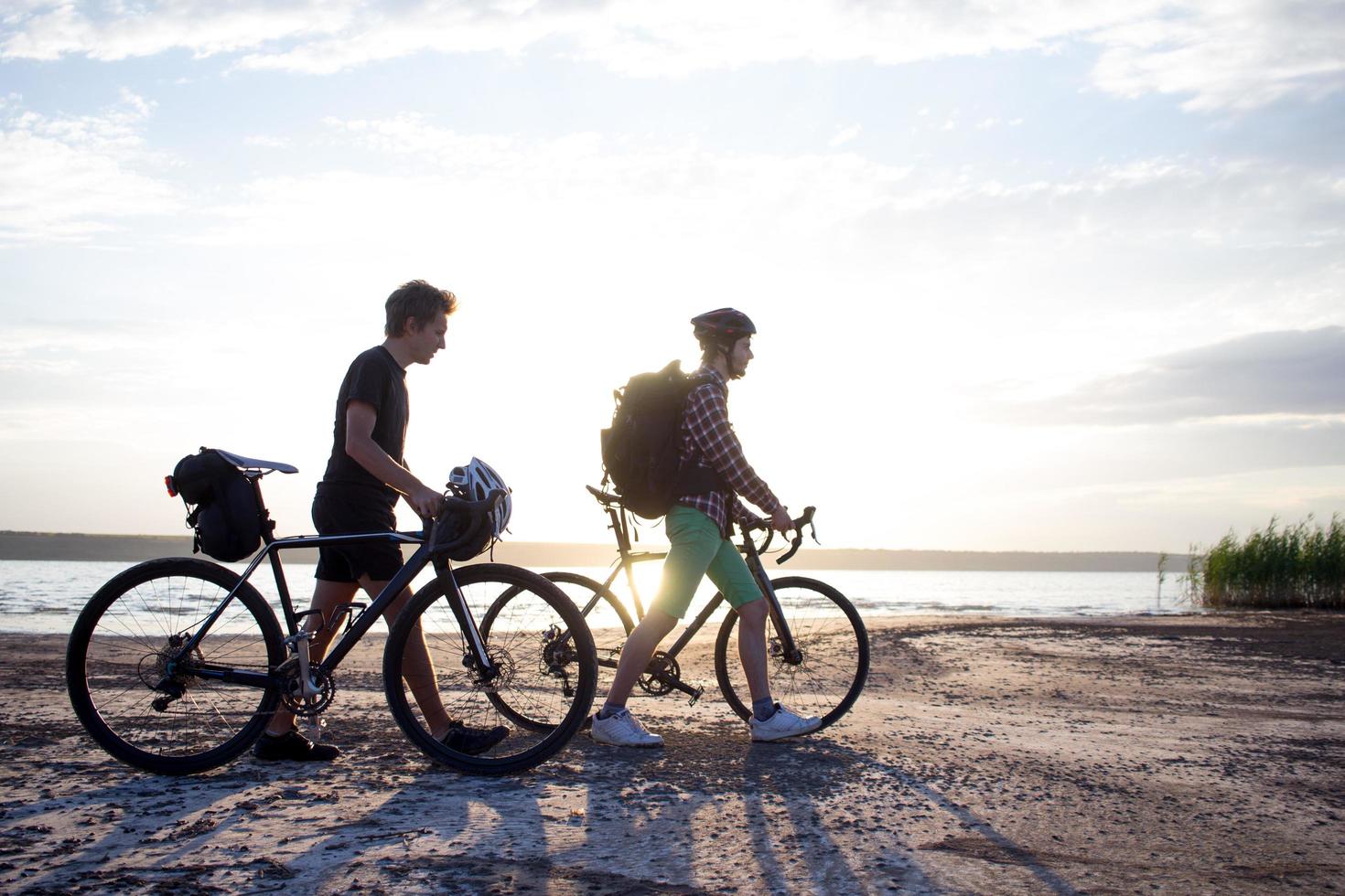 dos jóvenes en una bicicleta de gira con mochilas y cascos en el desierto en un viaje en bicicleta foto