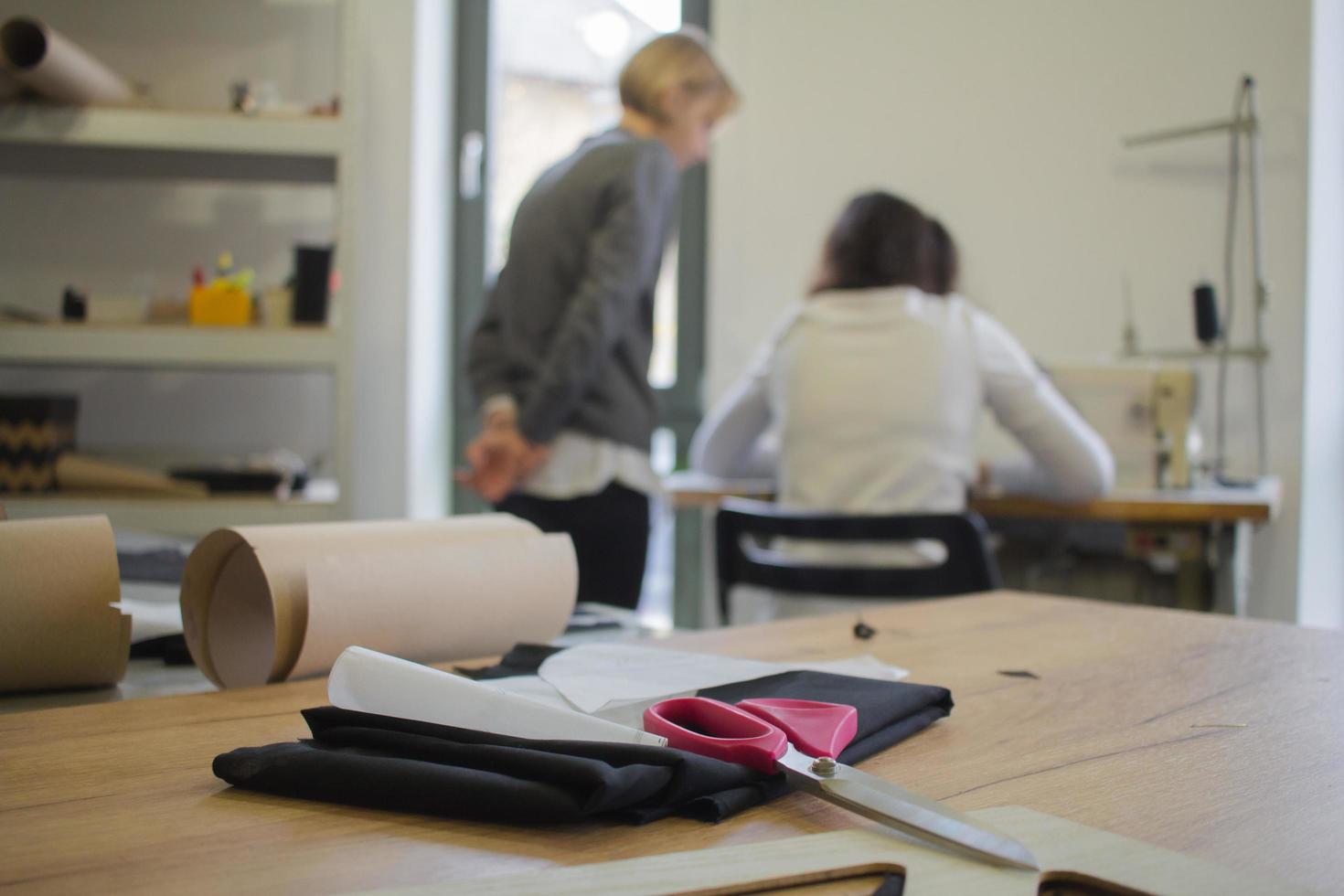 costurera en el trabajo sobre la mesa, sastre mujer trabaja en estudio con ropa foto